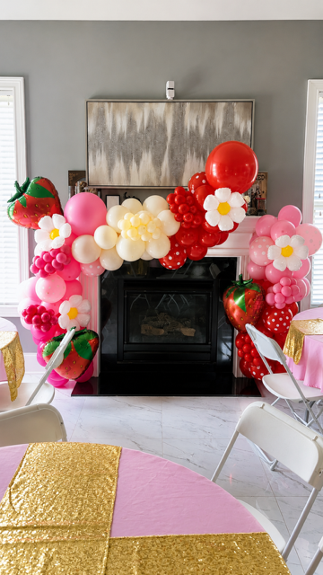 “Strawberry-themed balloon decoration with pink and red balloons for a celebration.”