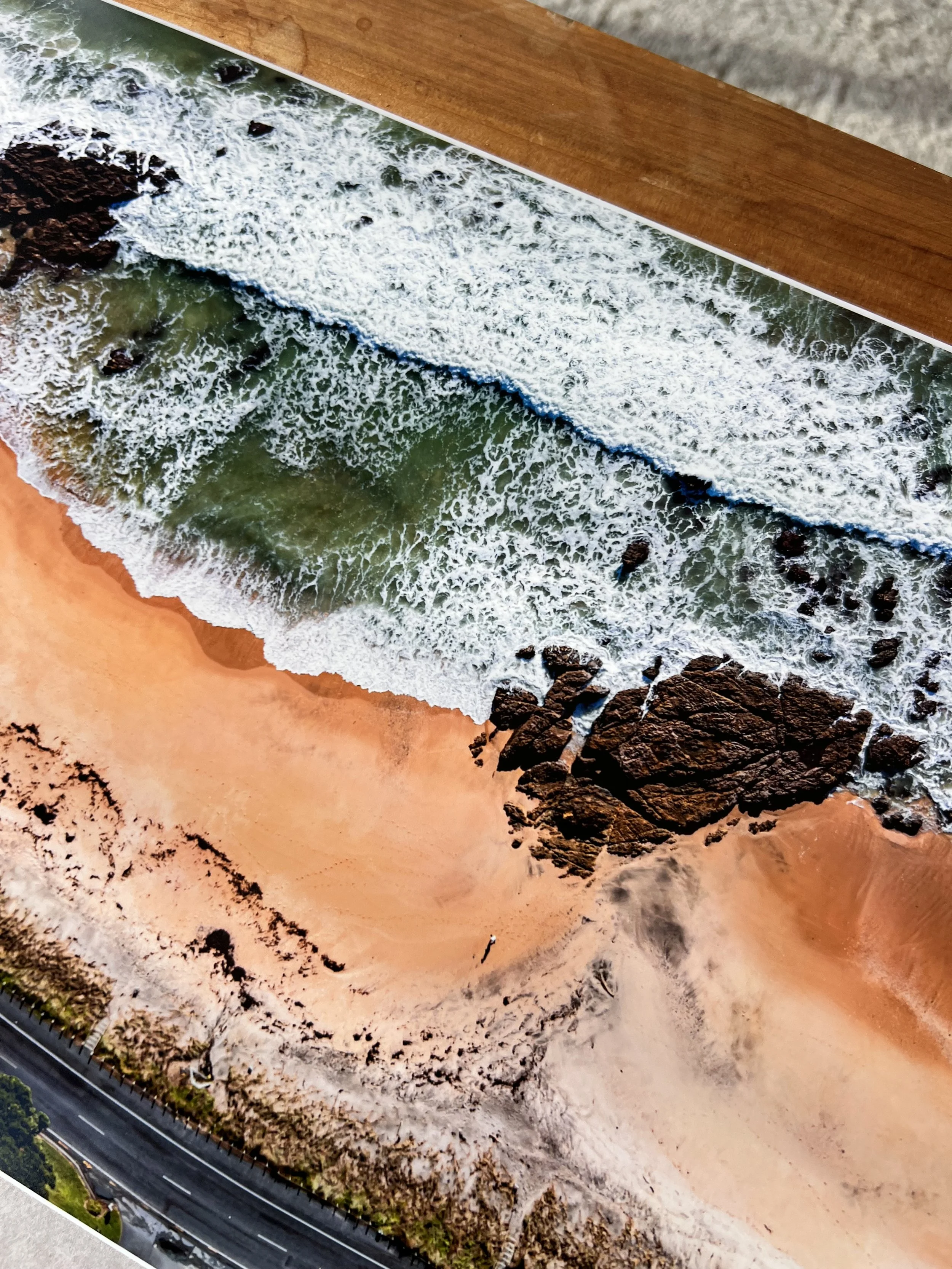 Aerial view of a coastline showing sandy beach, rocky shoreline, and waves crashing onto the shore.