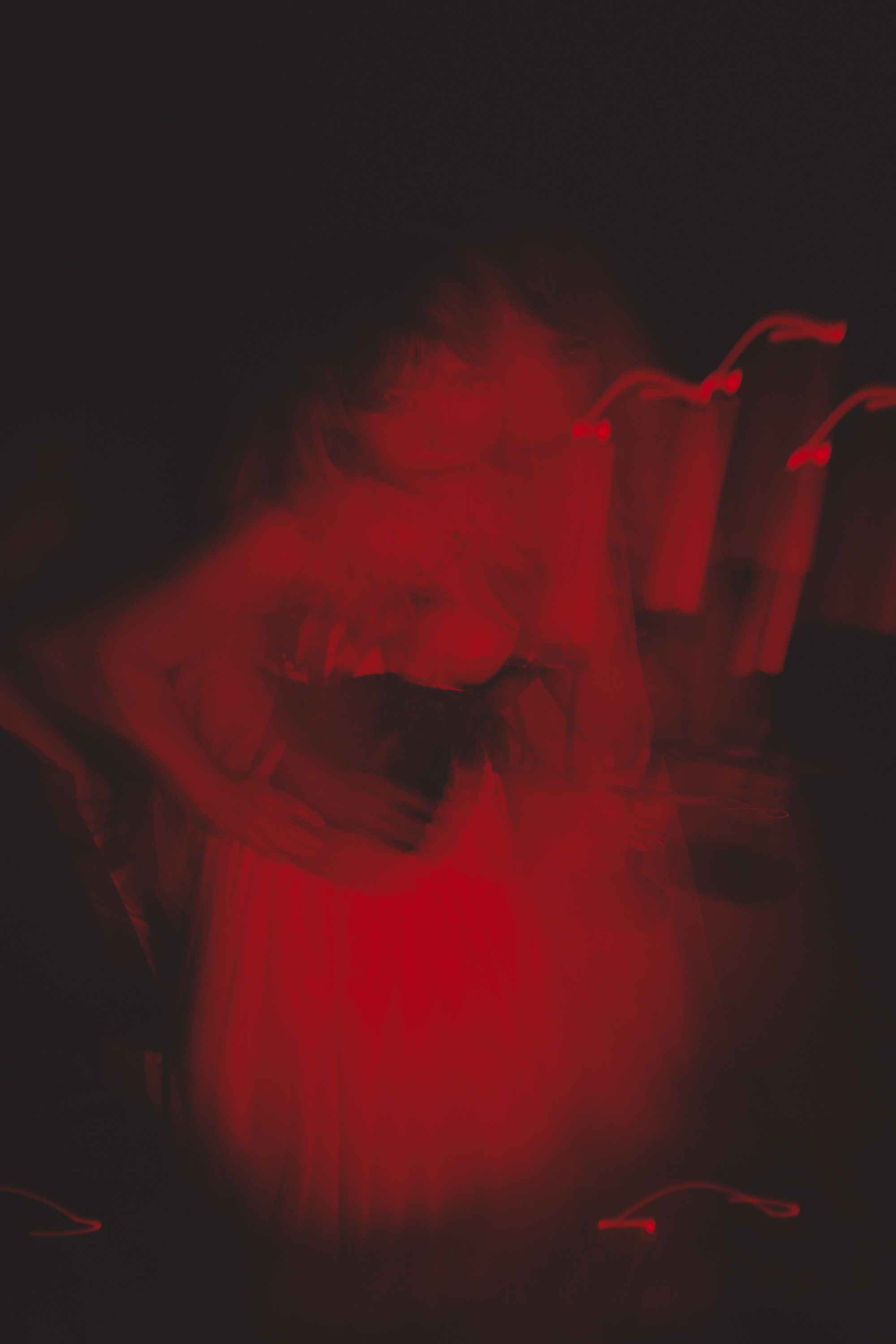 A person with glasses obscured by red and black swirling smoke or light effects.