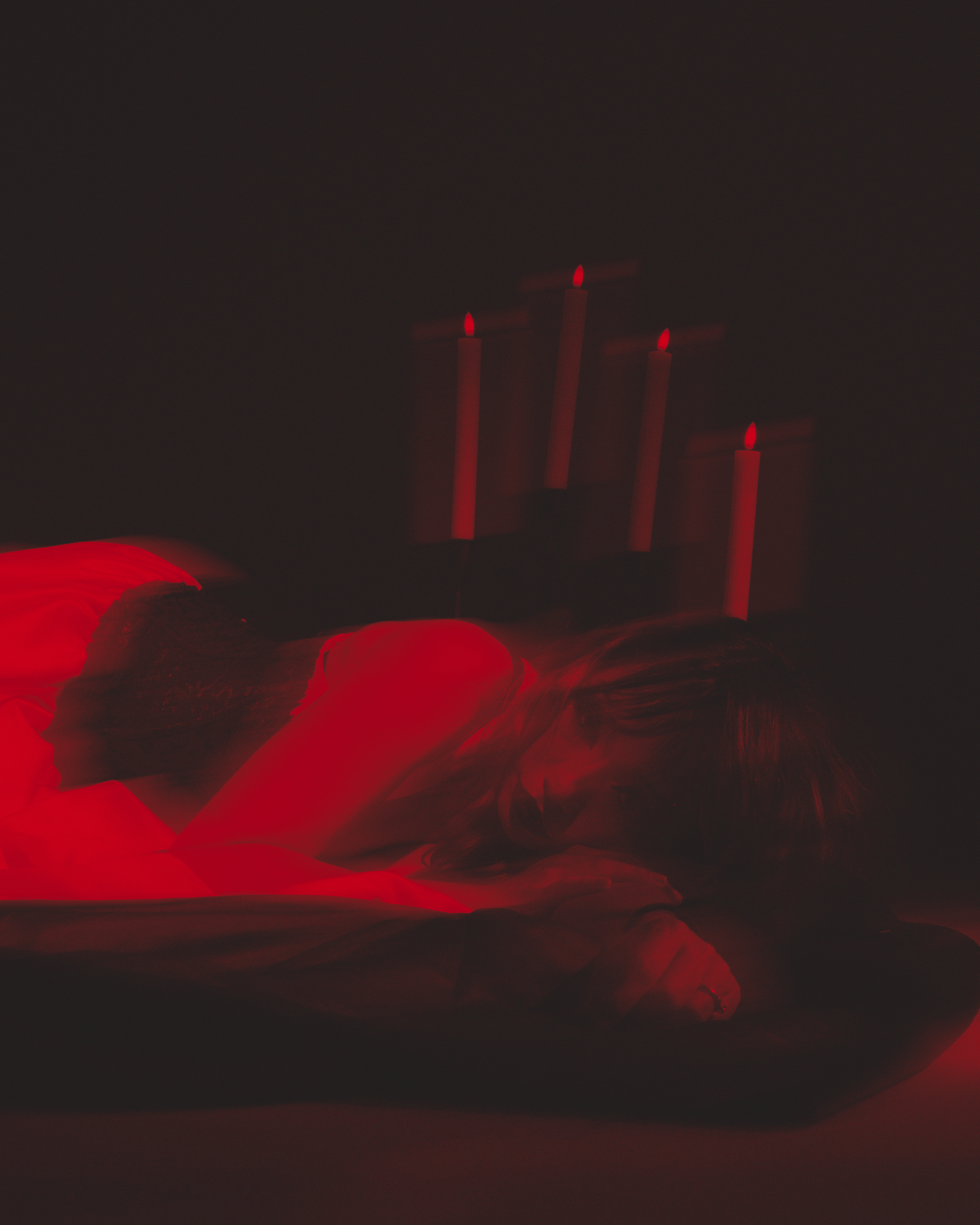 Dark image with red glowing electric candles in the background and petals in the foreground.