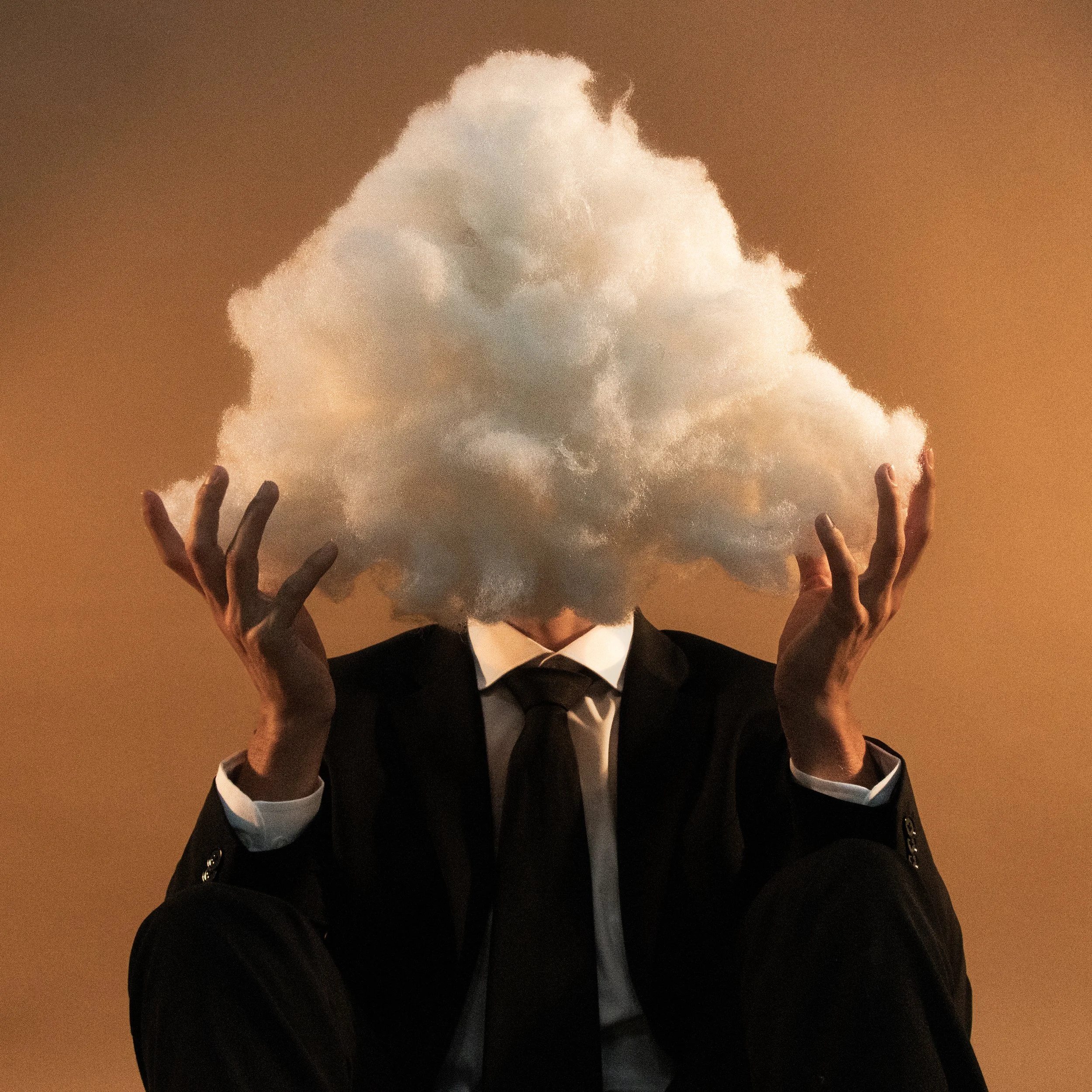 Person dressed in a black suit and white shirt holding up a large cloud of smoke or vapor against a gradient background.