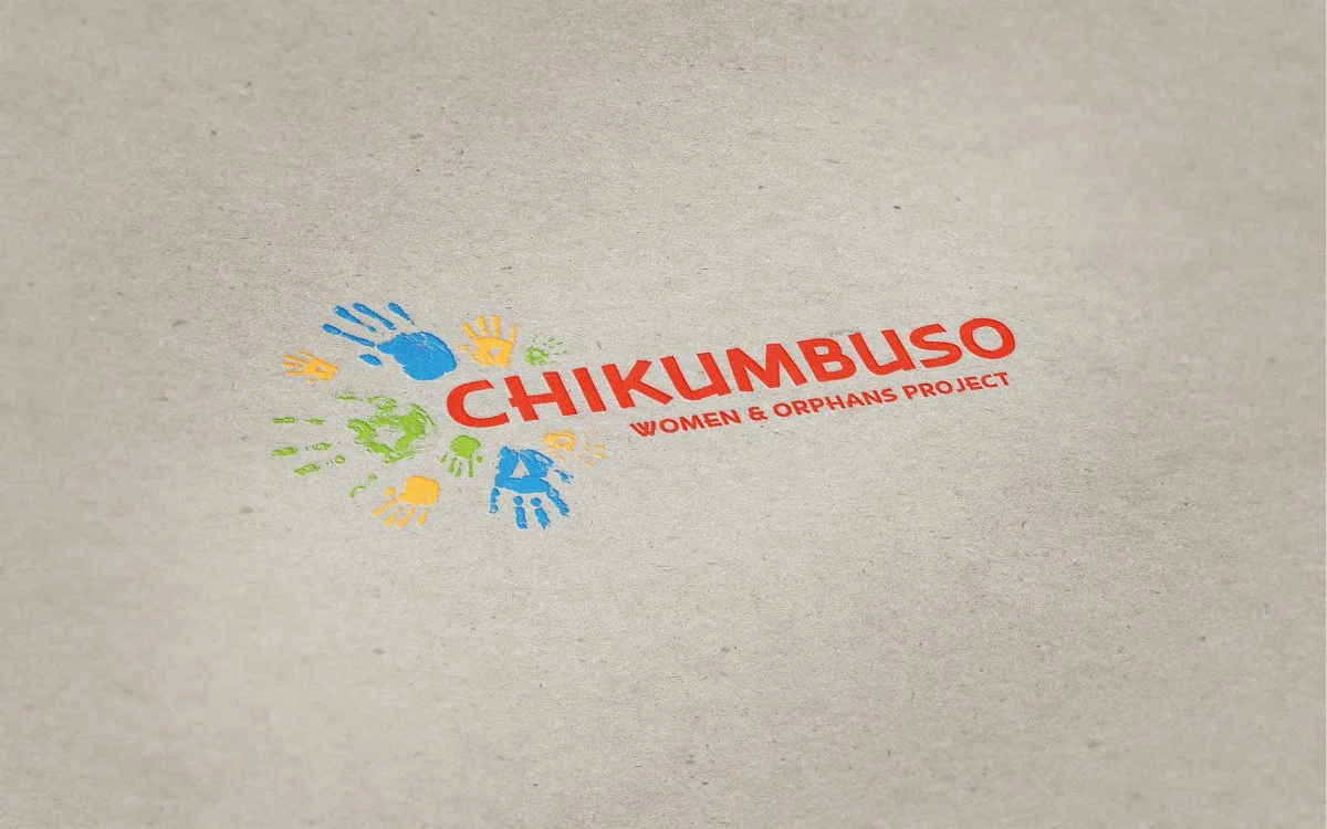 Colorful logo with the word 'CHIKUMBUSO' in red and smaller text 'Women & Orphans Project' underneath on a beige background, surrounded by multicolored handprints in blue, yellow, and green.