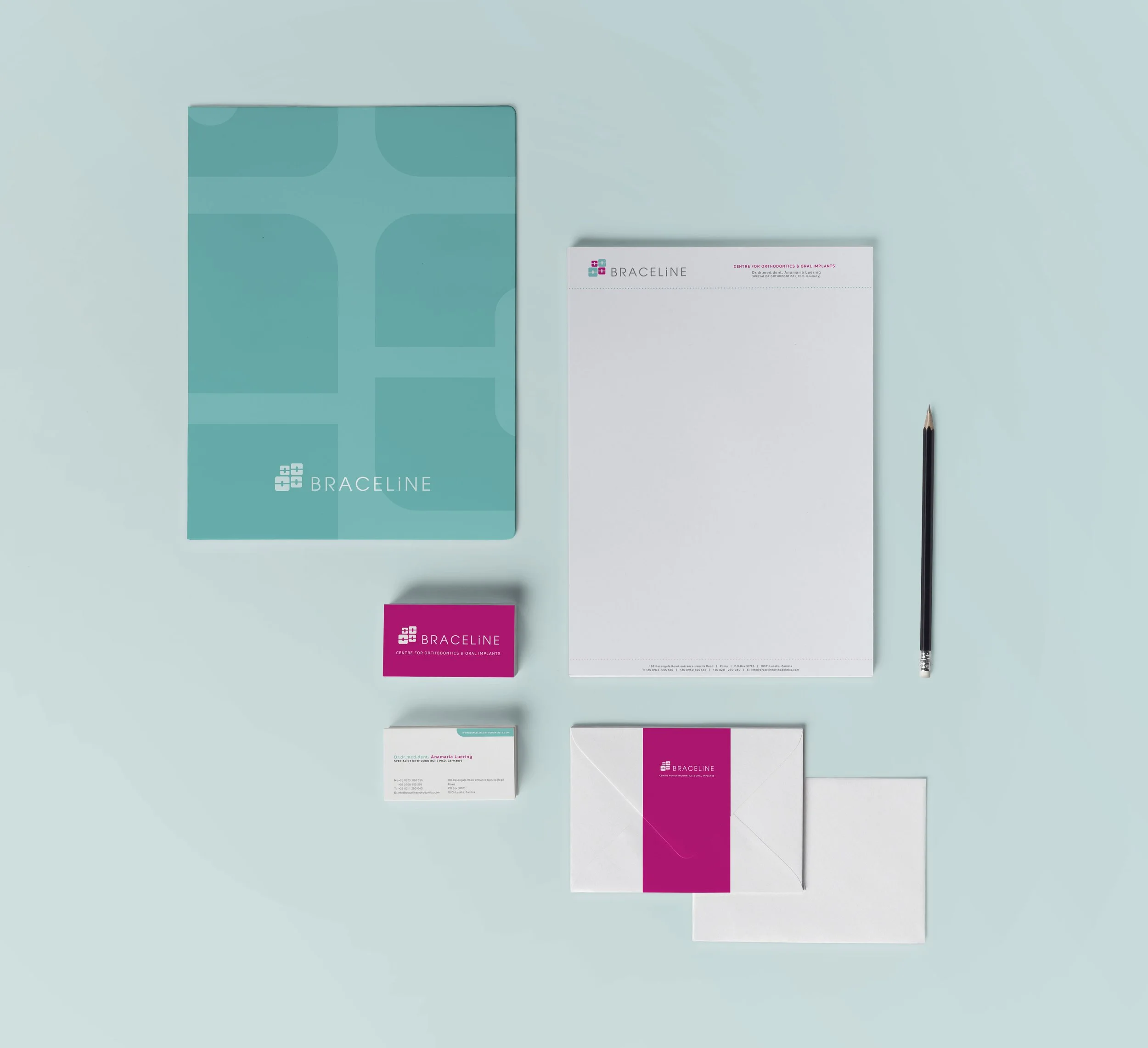 Flat lay of dental office stationery and branding materials, including a branded folder, letterhead, business cards, and a pen on a light blue background.
