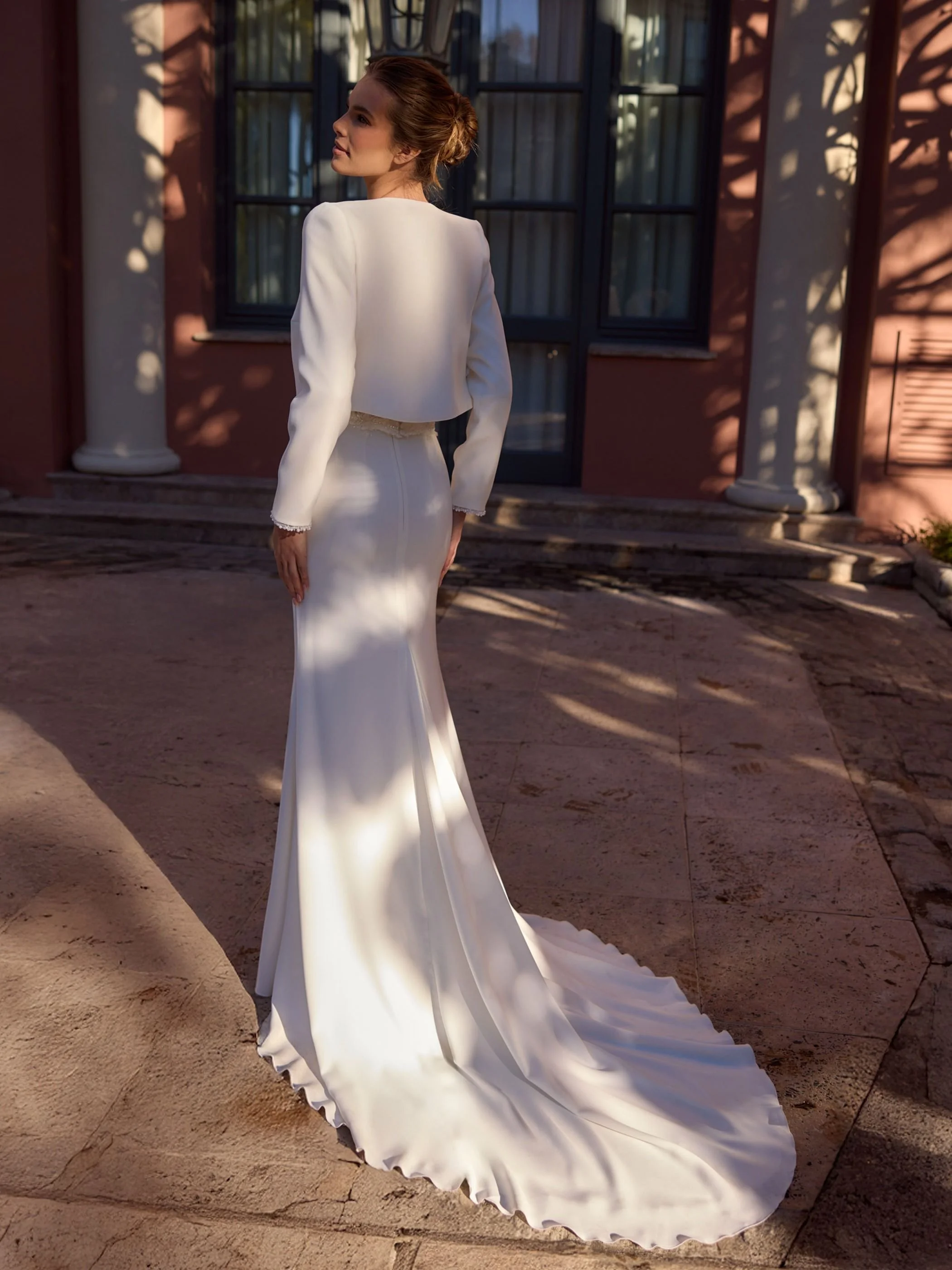 Summit back view of crop beaded edge jacket Discover the Summit Bridal Skirt, a luxurious stretch crepe mermaid wedding skirt featuring a flattering silhouette and elegant cathedral-length train.