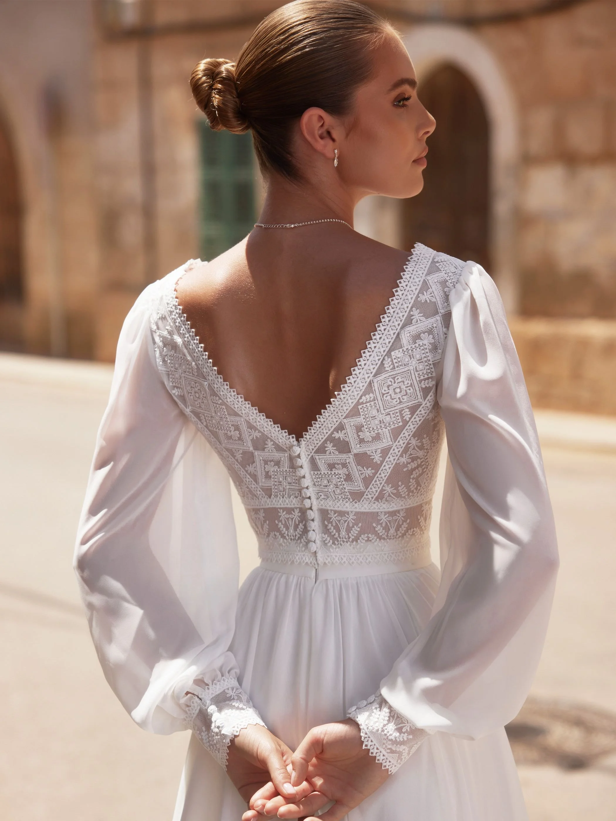 Urban top back view showing bride with hands behind her back and long ciffon sleeve