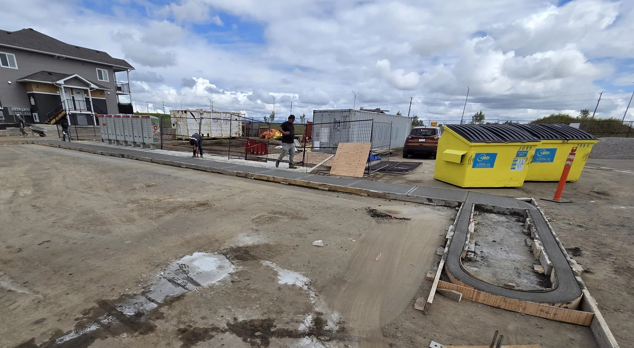An active commercial concrete installation featuring a long multi-family development sidewalk and precision radius curb finishes in Stony Plain near Spruce Grove.
