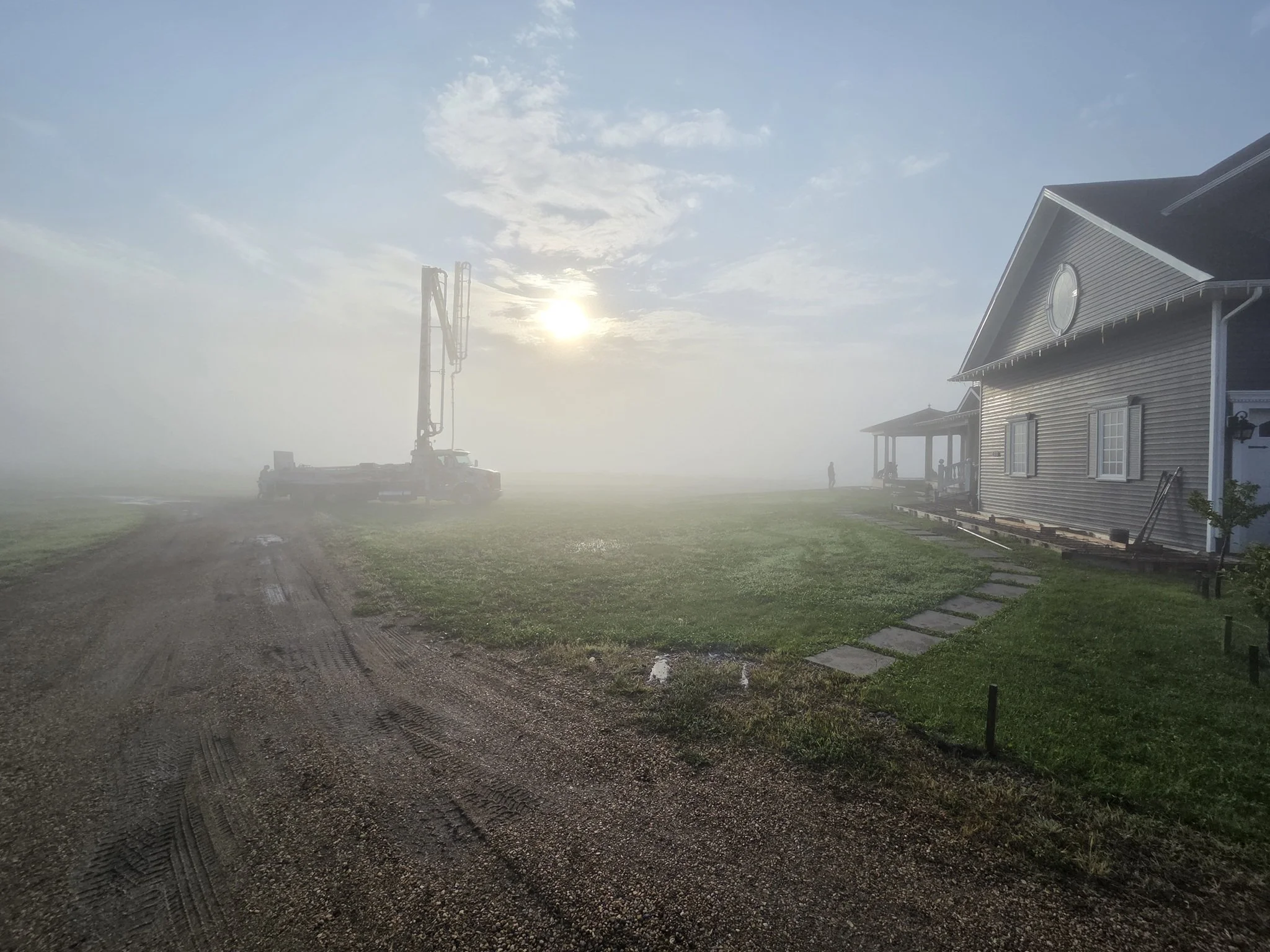 A professional concrete contractor crew and heavy-duty boom pump truck preparing for a large-scale residential estate concrete pour on an Alberta acreage.