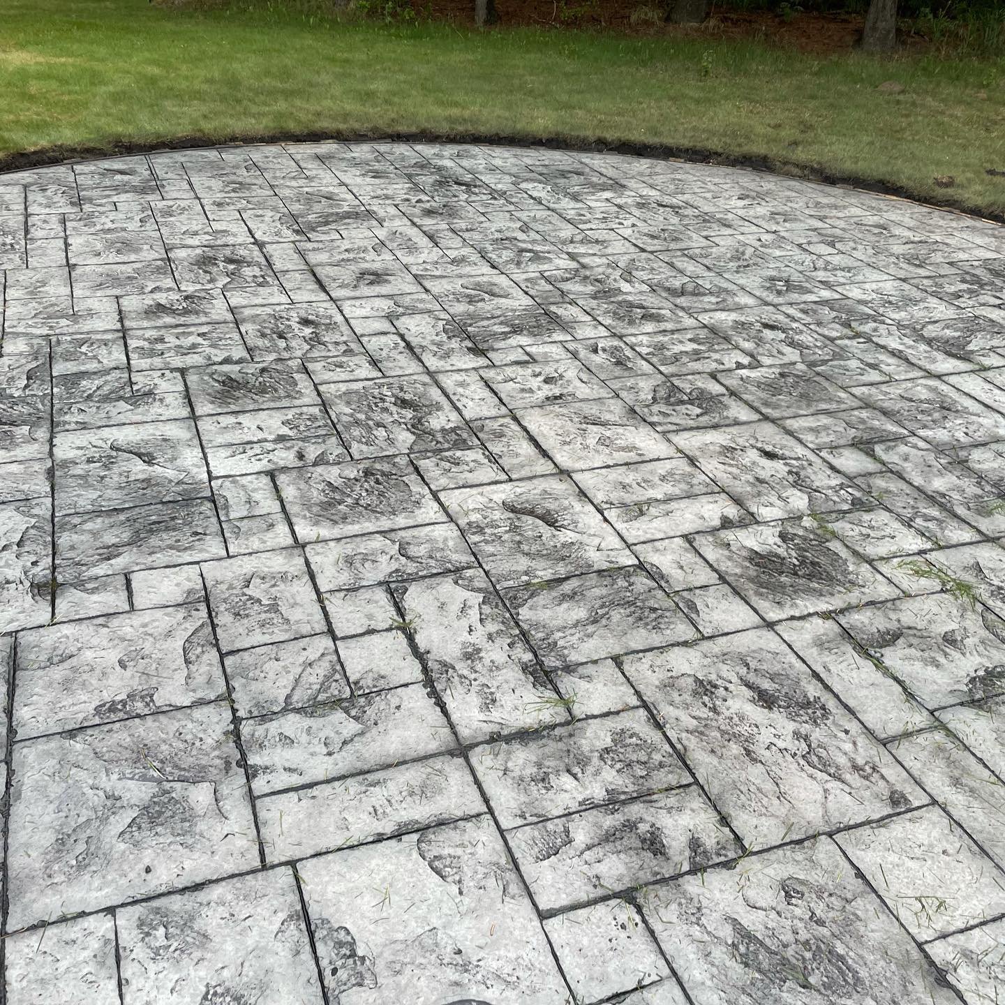 A completed architectural ashlar slate stamped concrete patio featuring premium textured patterns and a clean dark charcoal release accent finish in the Greater Edmonton area.