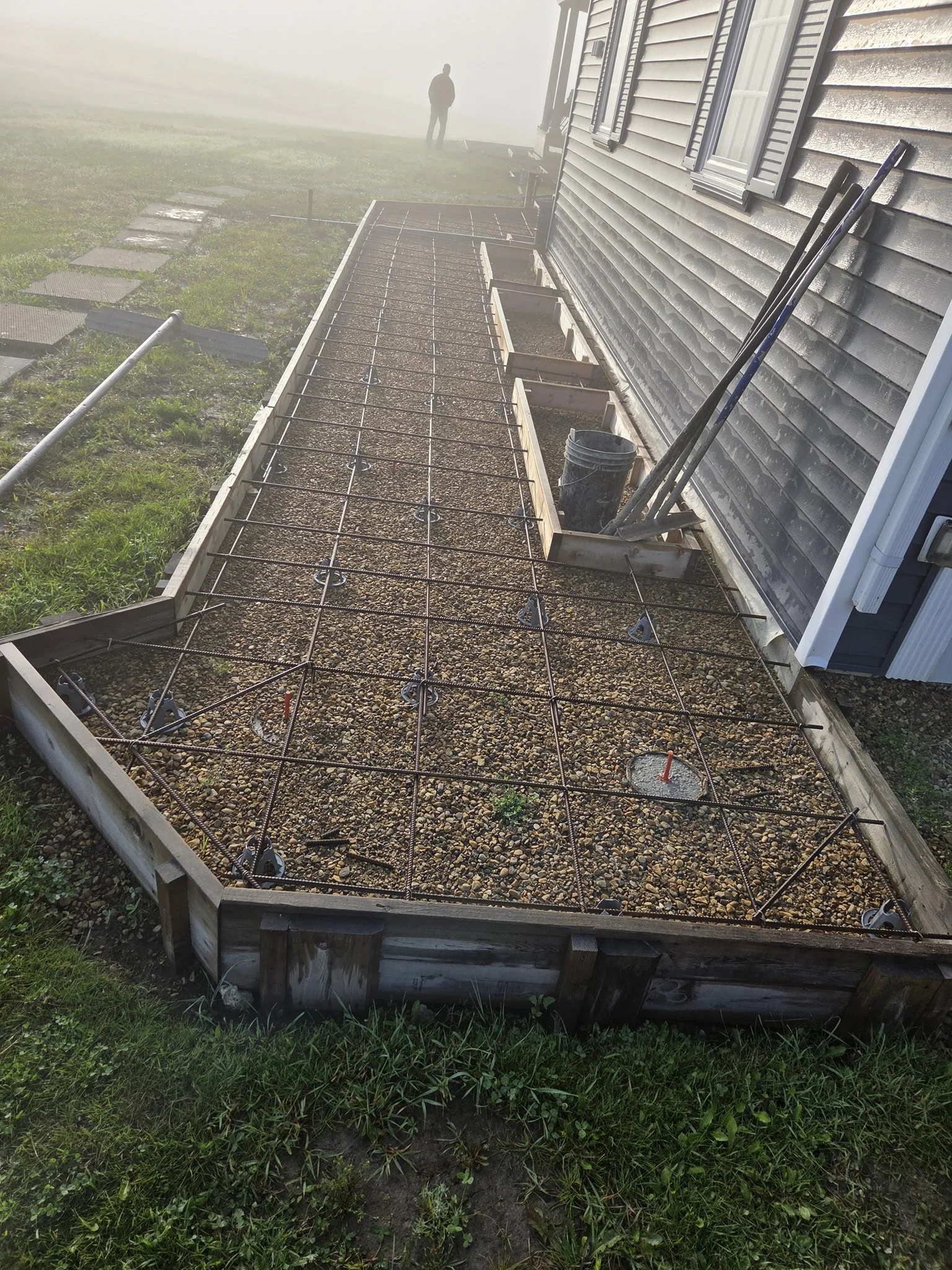 Professional concrete crew preparing immaculate formwork and rebar grid reinforcement for a large-scale custom residential walkway on an Alberta acreage estate.
