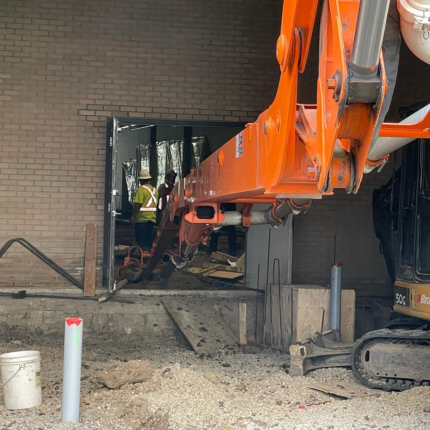 An active commercial concrete placement utilizing a boom pump truck line routed directly through a building entryway for an interior slab pour in the Greater Edmonton area.