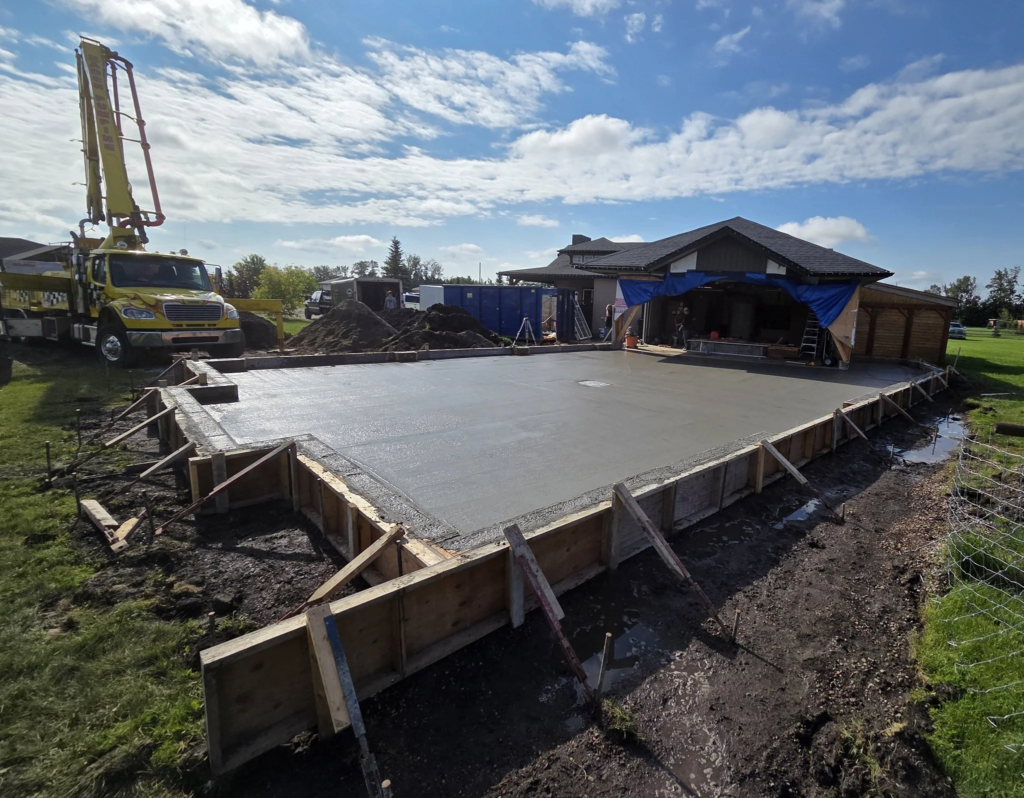 A commercial-grade concrete boom pump truck finishing a massive custom residential driveway slab pour on a luxury Parkland County acreage near Spruce Grove.