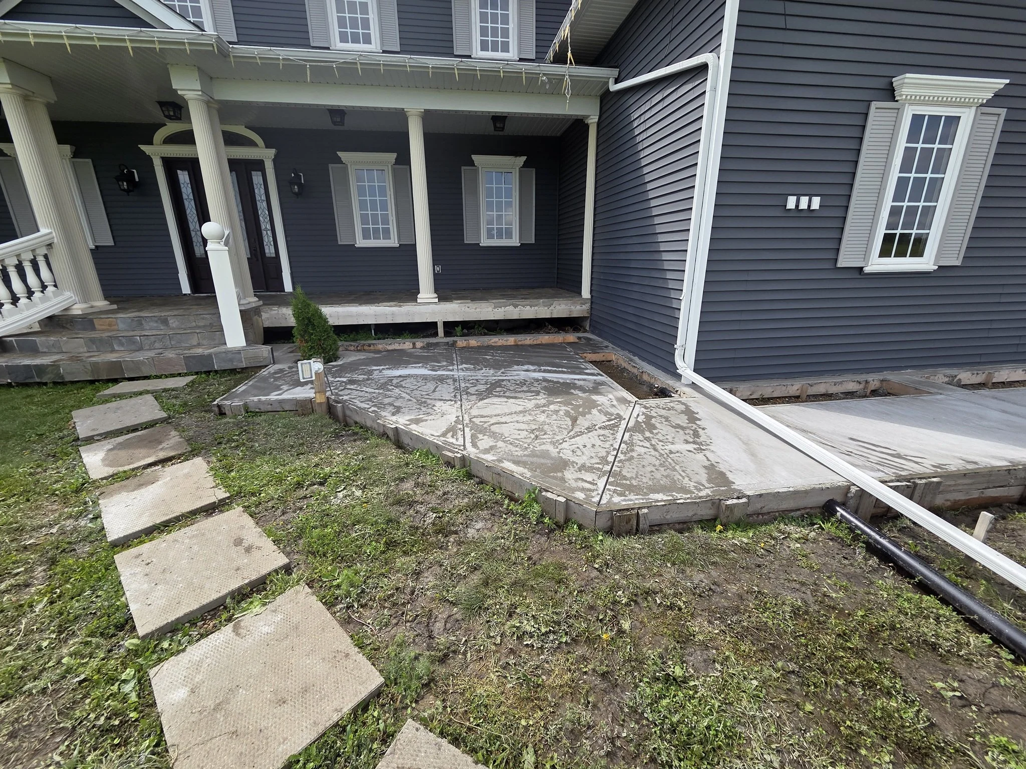 A freshly poured and custom-jointed architectural concrete sidewalk wrapping around a luxury residential acreage home entry in Alberta.