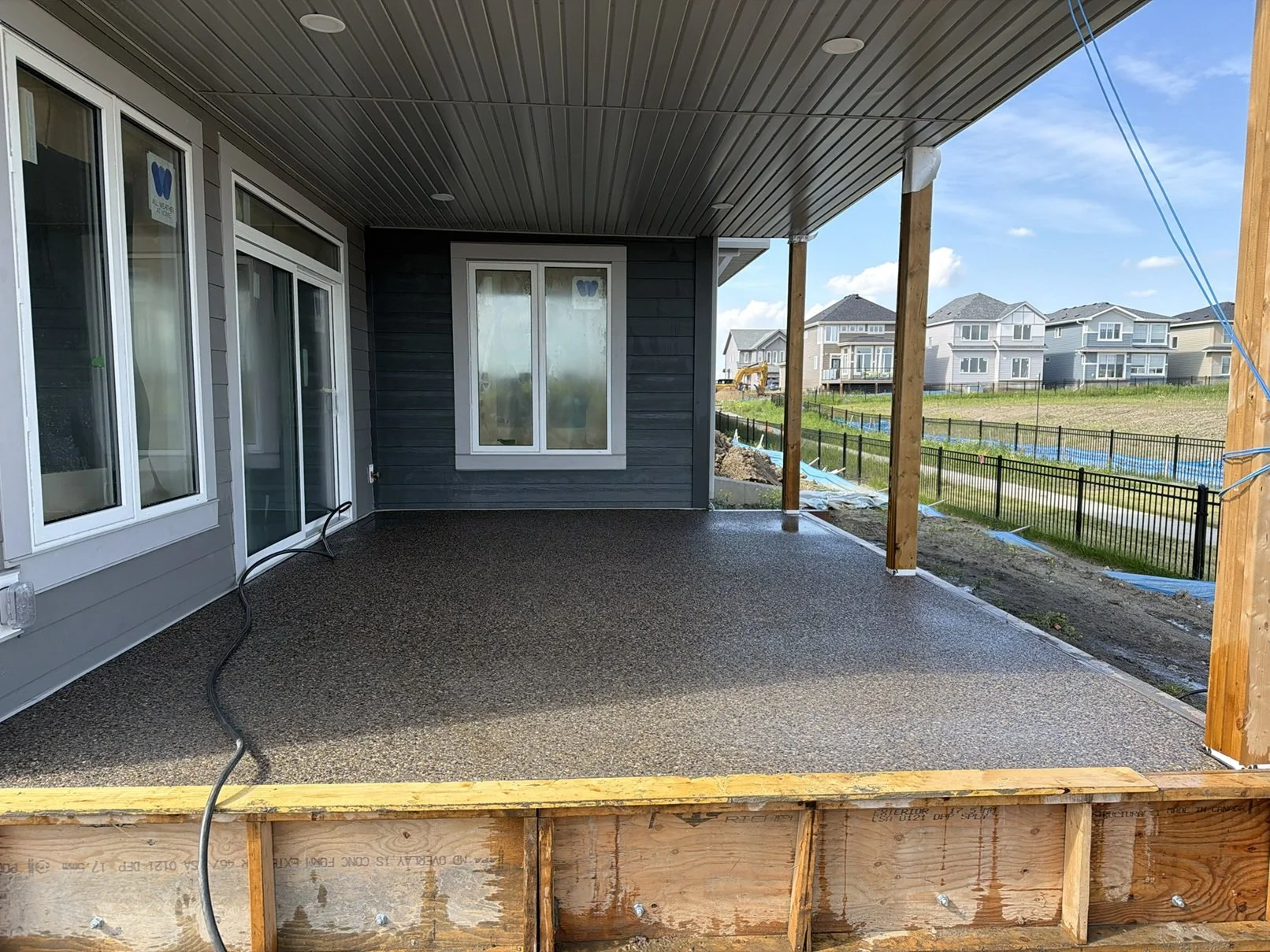 A clean, freshly poured exposed aggregate concrete patio by D&M Concrete, featuring a smooth, pebble-textured surface in an Edmonton backyard