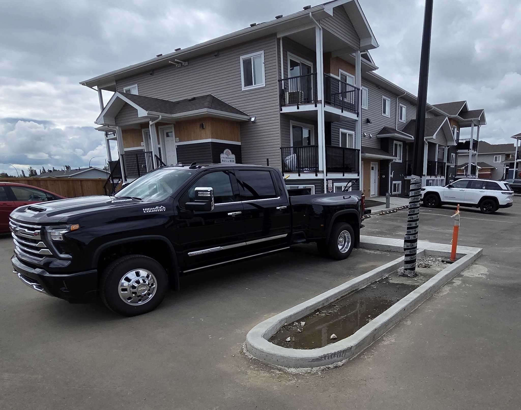 A completed commercial concrete parking lot island featuring a smooth radius curb and integrated light pole standard base for a multi-family development in Stony Plain near Spruce Grove.