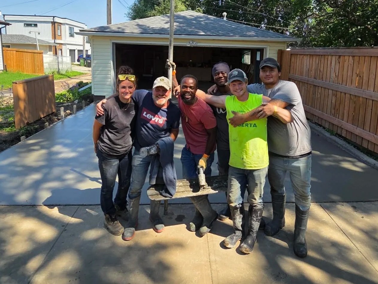 The DM Concrete professional 6-man concrete placing and finishing crew standing together on a freshly completed structural flatwork placement in Spruce Grove.