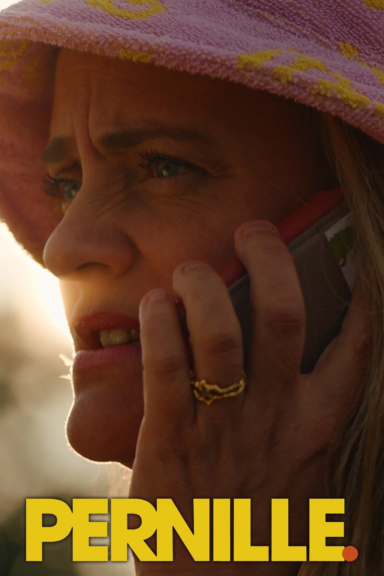 Close-up of a woman with a pink towel on her head, holding a phone to her ear, with the name "PERNILLE" in large yellow letters at the bottom of the image.