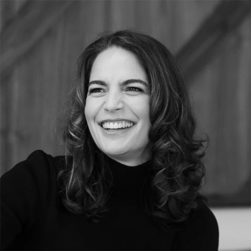 Black and white photo of a woman with curly hair smiling.