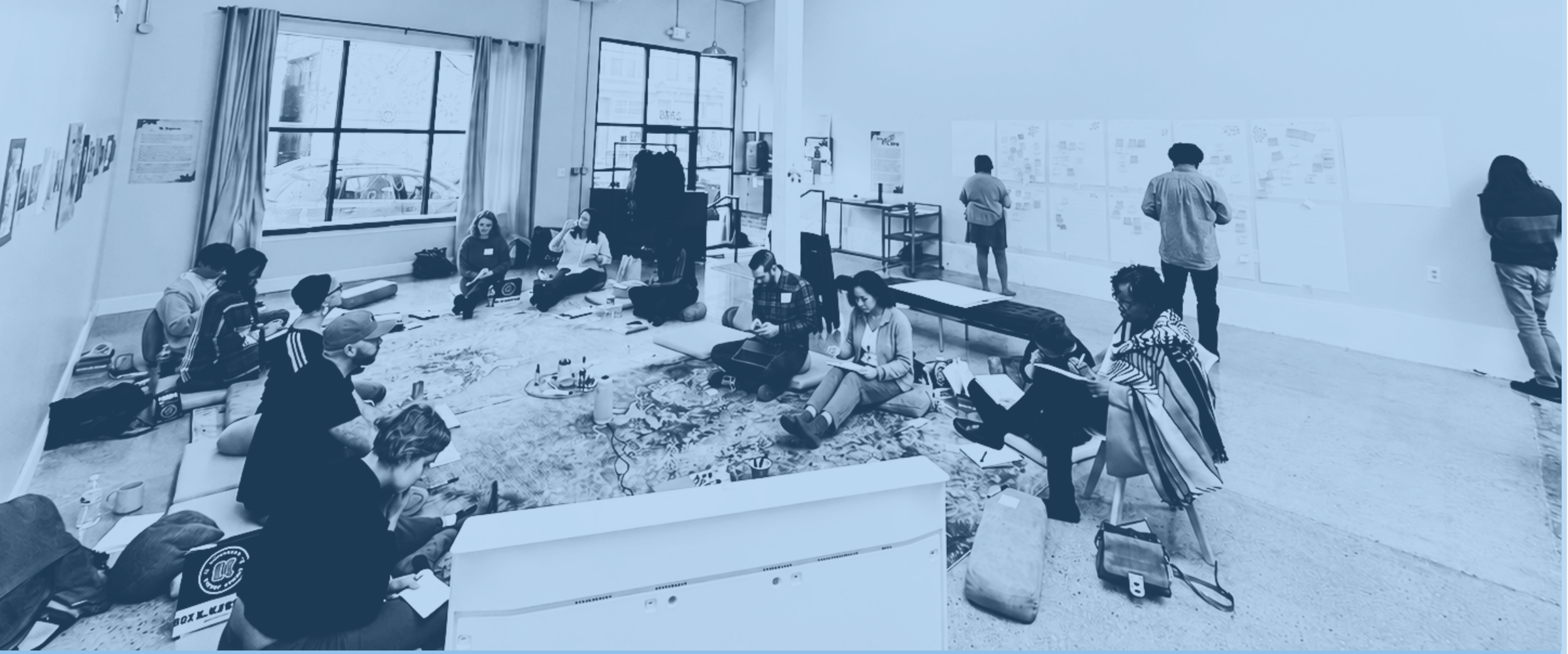 People participating in a collaborative workshop in a light-filled gallery space.