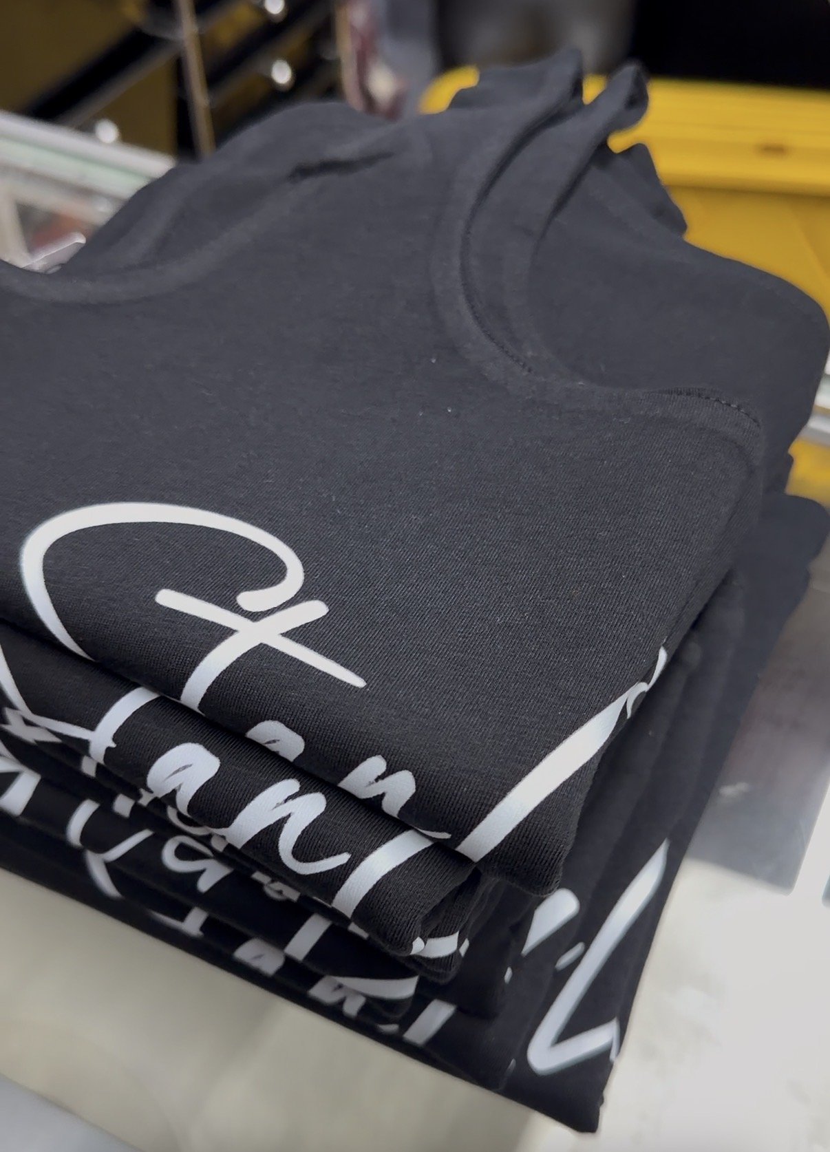 Stack of folded black t-shirts with white printed text.