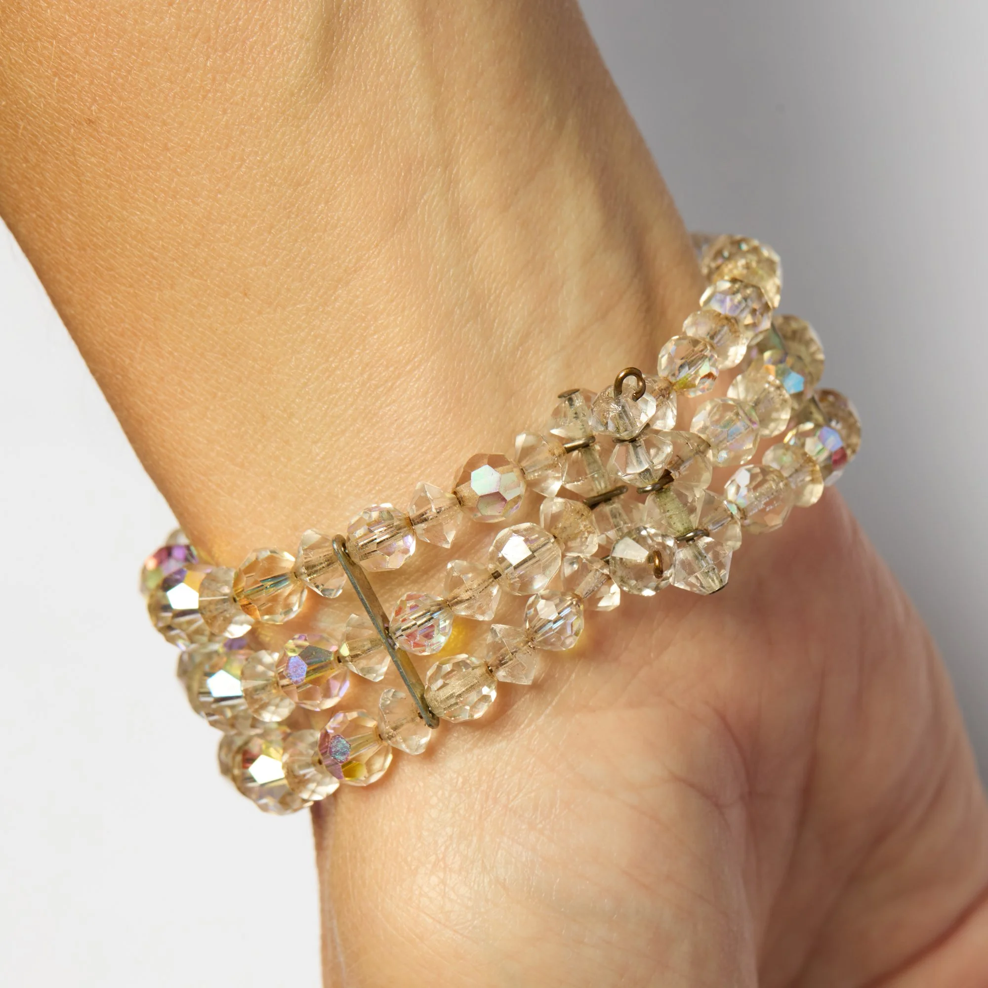 Close-up of a person's wrist wearing a jewelry bracelet with multicolored, faceted crystal beads.