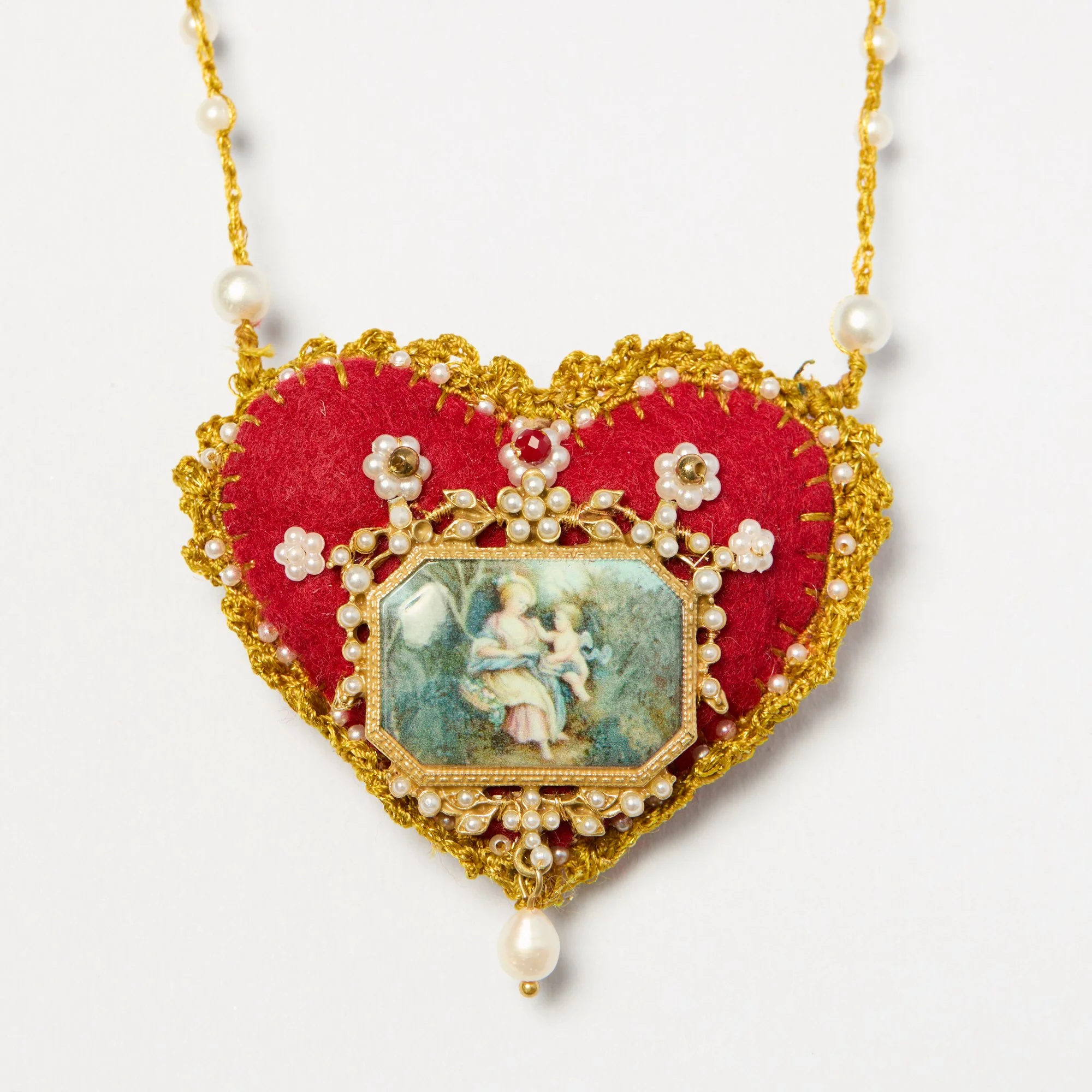Close-up of an ornate necklace with gold thread, pearls, and a pendant featuring a classical painting of two women.