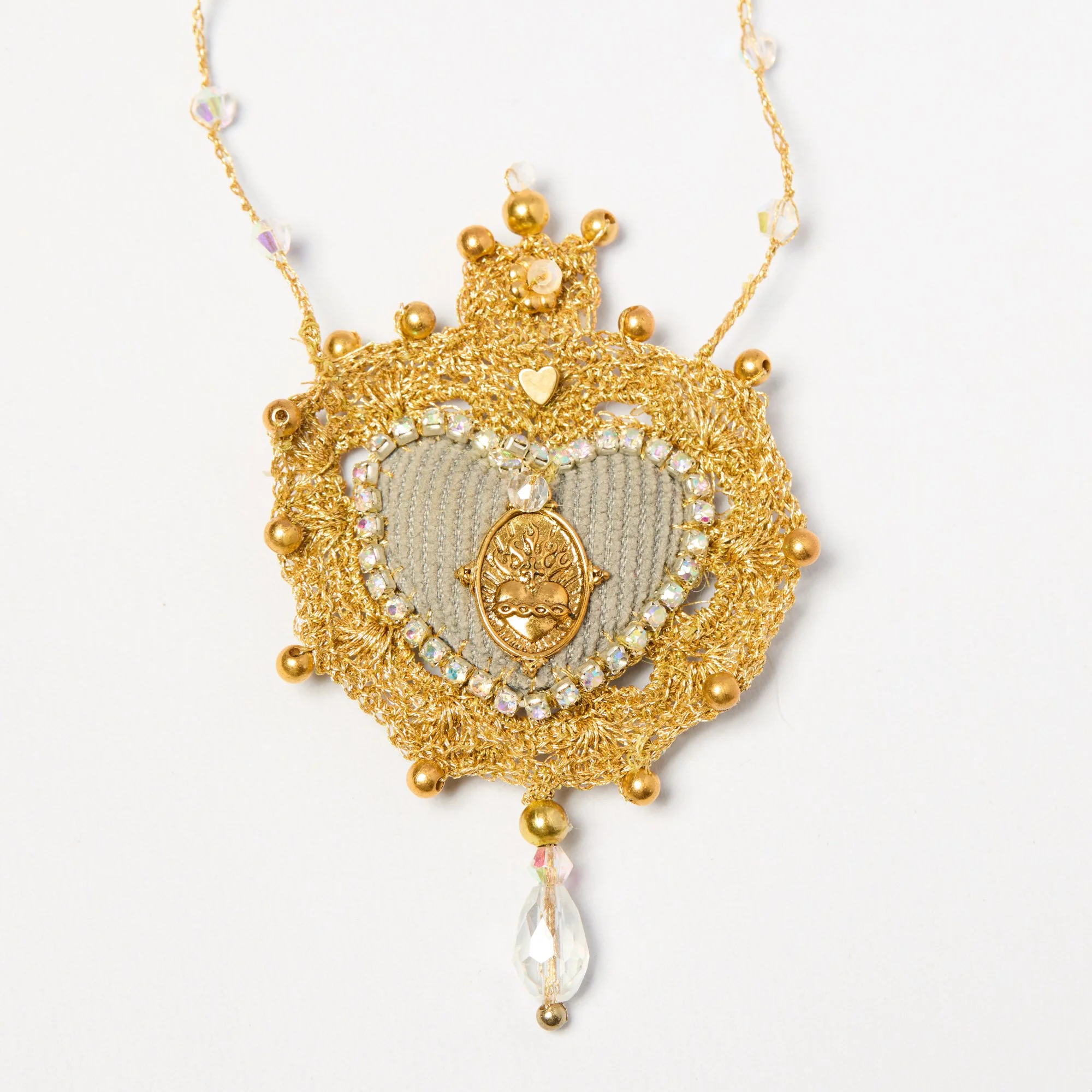 Gold and clear crystal necklace with a centerpiece featuring a small gold heart and an oval charm hanging from a decorative chain.