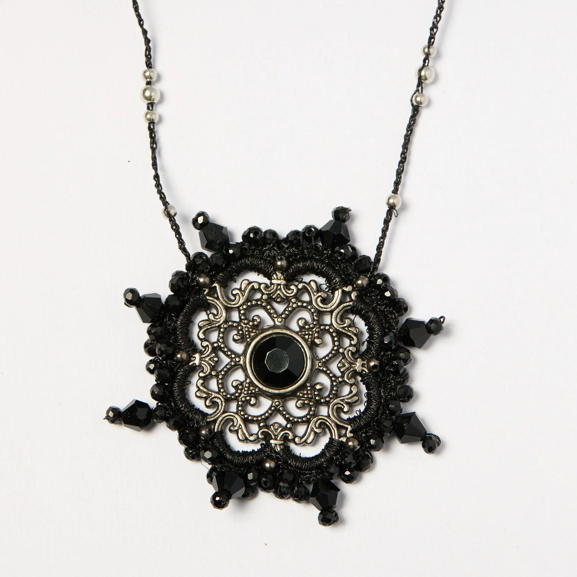Black and silver beaded necklace with intricate silver pendant and dangling beads on a white background.