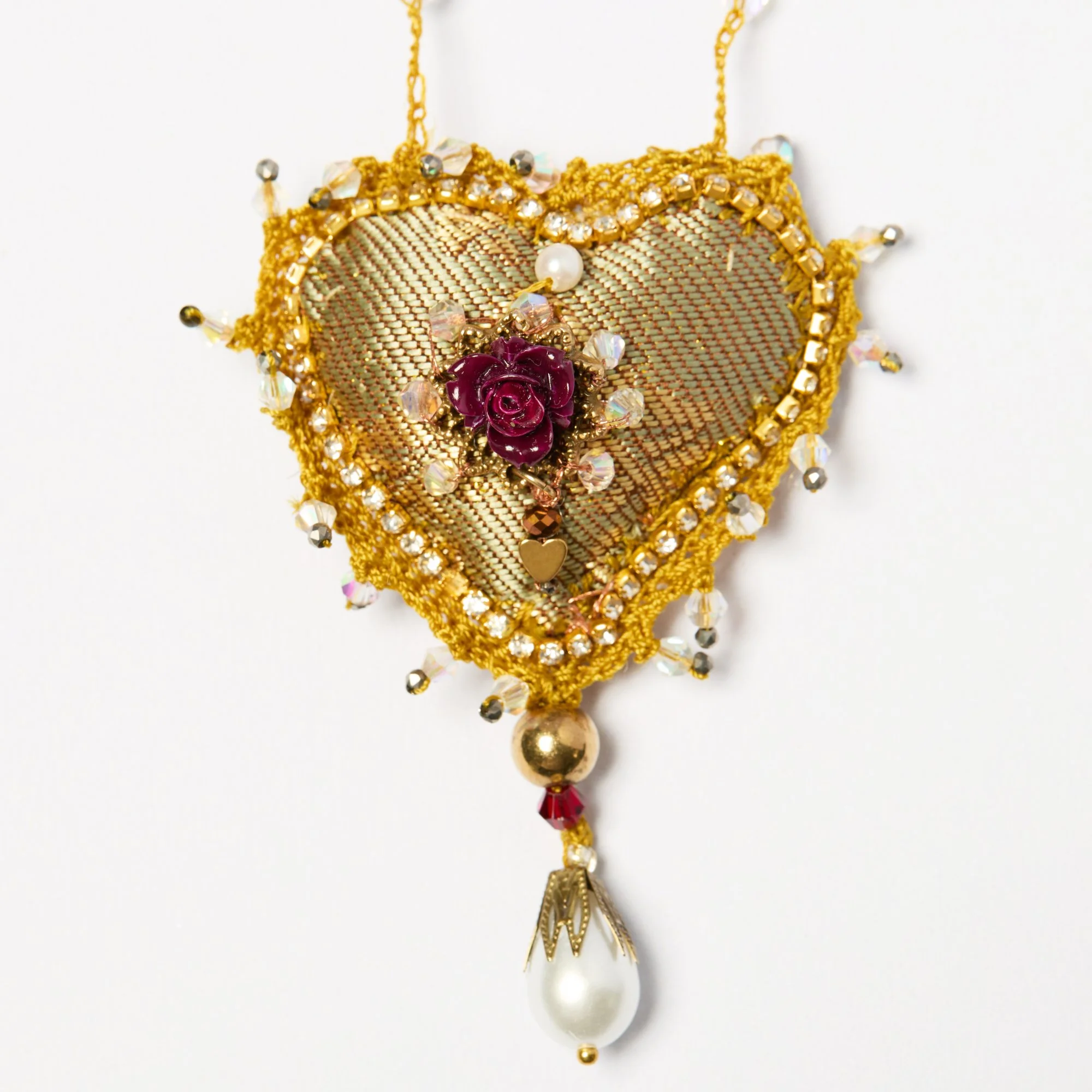 A decorative gold-colored necklace with beads, a rose charm, and pearls, hanging against a white background.