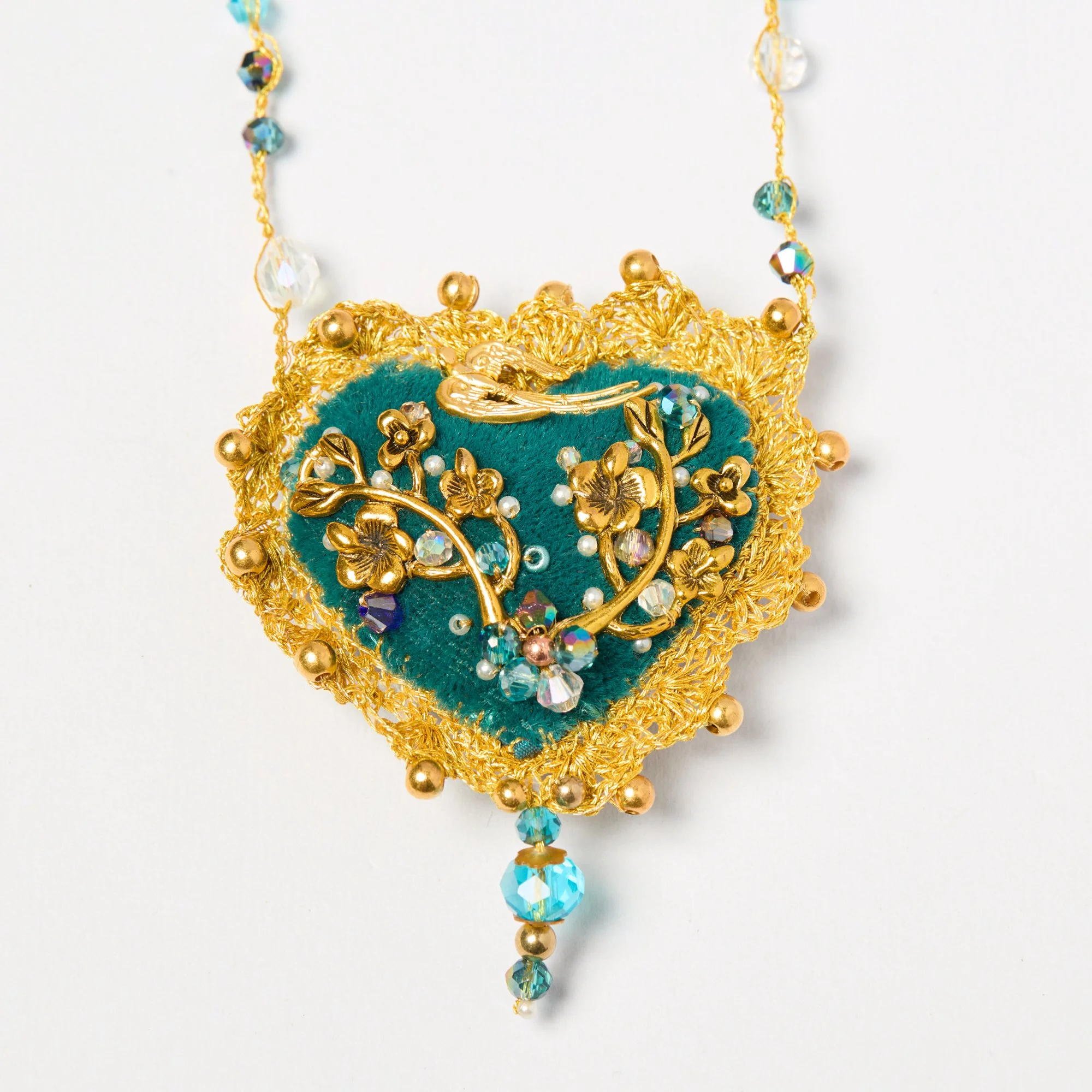 Elegant necklace with gold floral design, blue velvet base, and sparkling blue and clear beads on a white background.