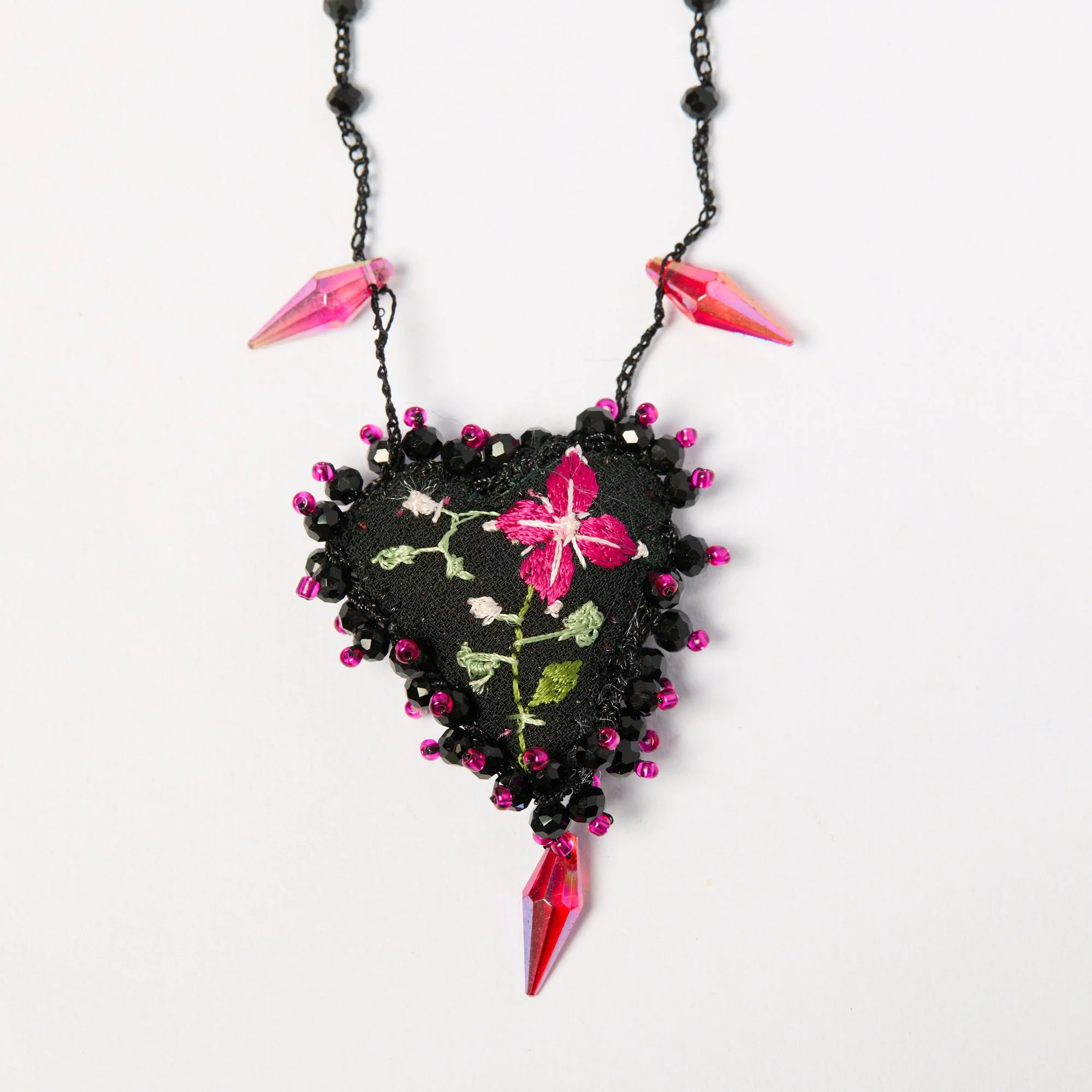 Pink and black beaded necklace with a pink crystal pendant, featuring embroidered floral detail.