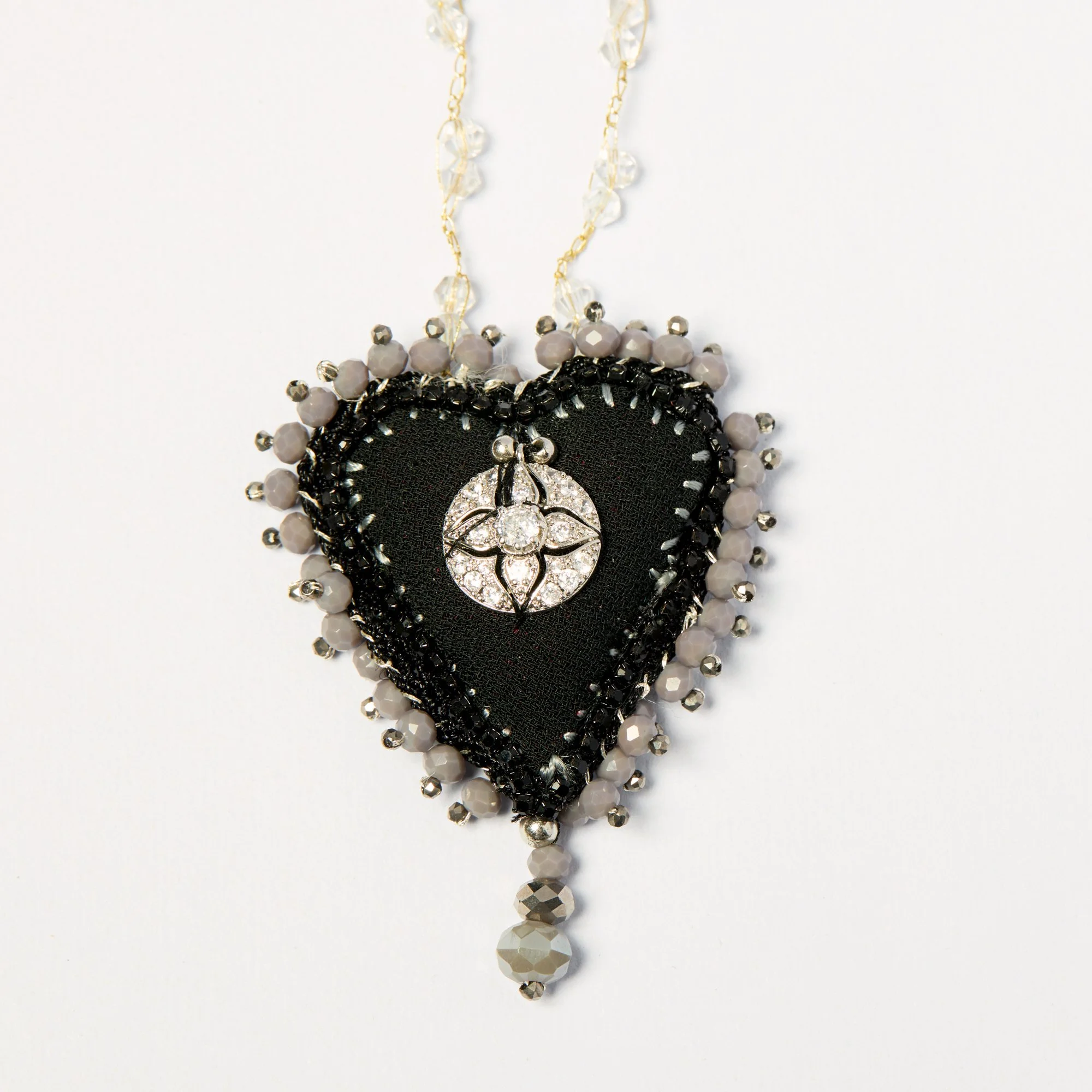 Close-up of a decorative necklace with black, white, and clear beads and a silver pendant featuring a floral design.