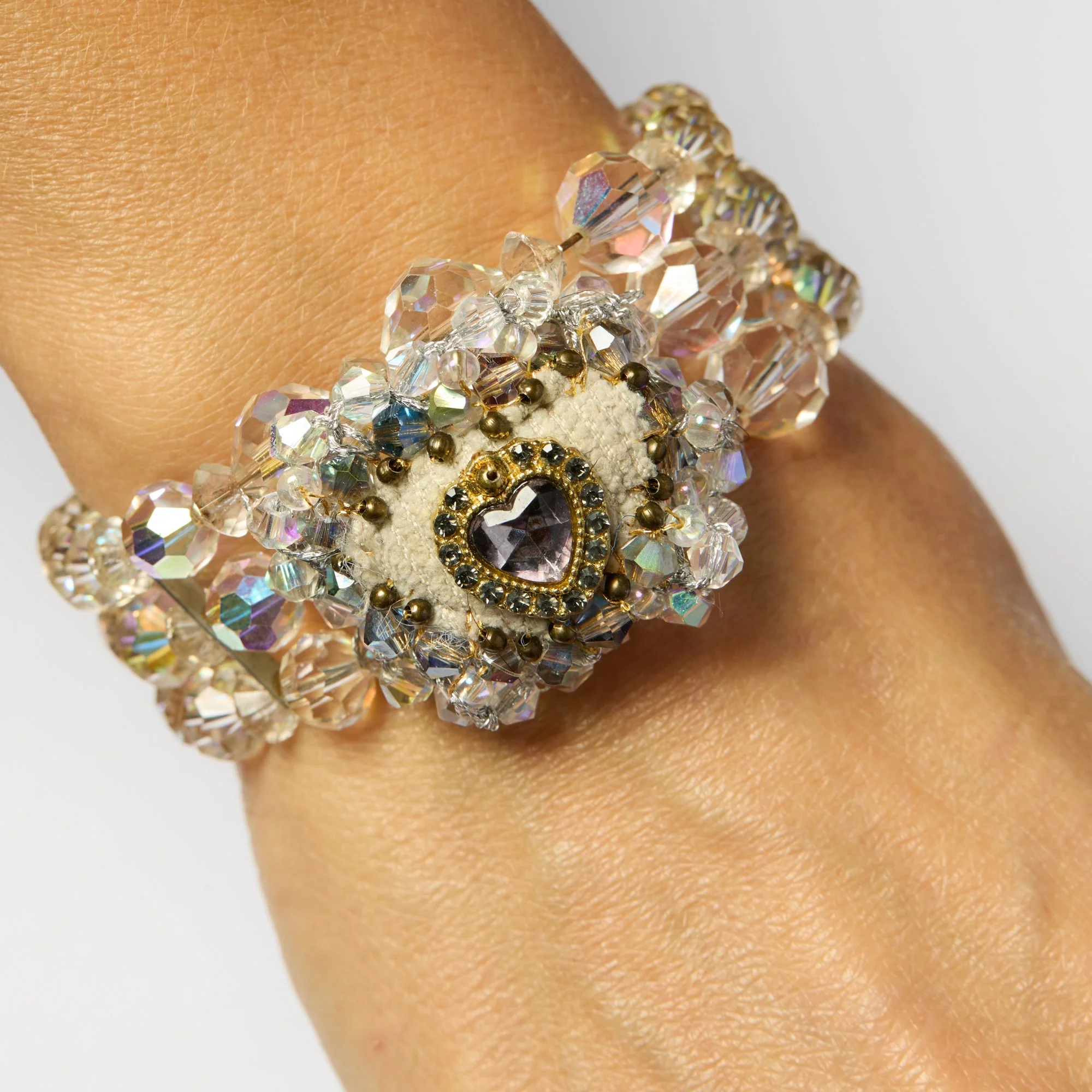 Close-up of a person's wrist wearing an elaborate bracelet with large faceted crystals and small gold beads.