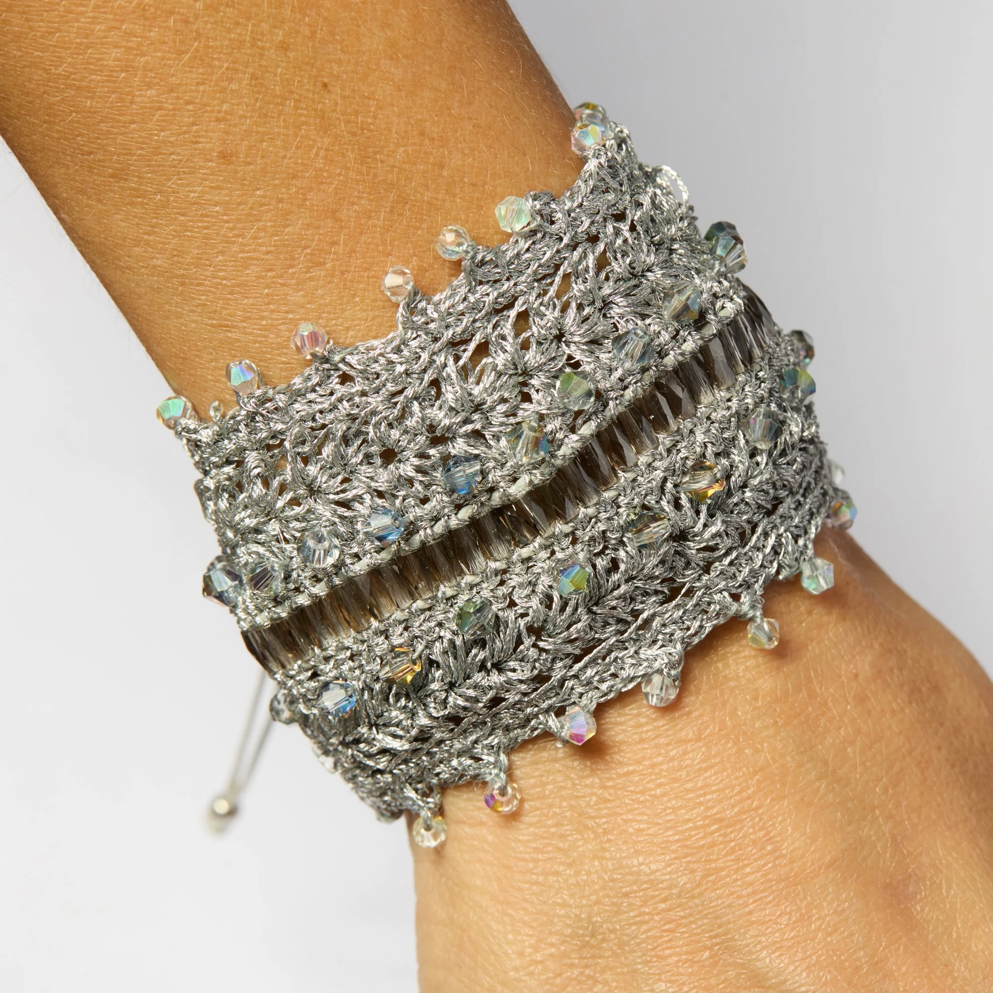 Close-up of a person wearing a silver and crystal bracelet with dangling bead charms.