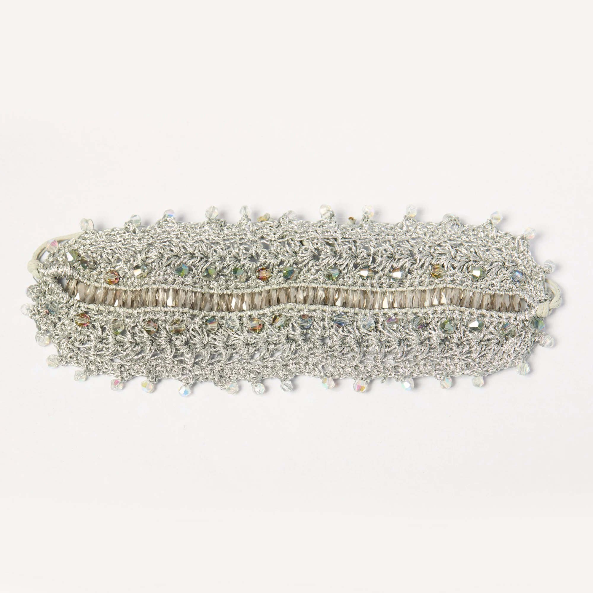 Close-up of a silver headband decorated with multicolored crystals, lying on a white background.