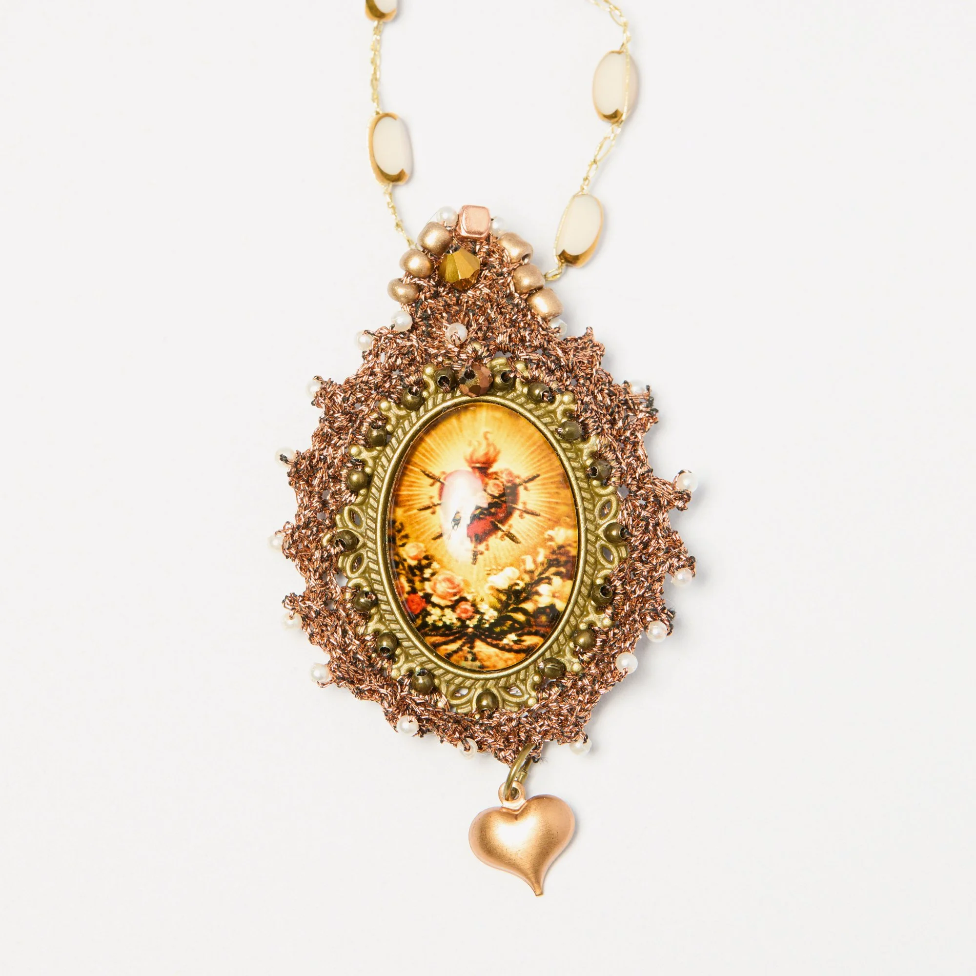 A colorful necklace with a gold chain, beige and gold oval beads, a cluster of metallic beads, and a pendant with a picture of a person and landscape surrounded by decorative elements and a small heart-shaped charm at the bottom.