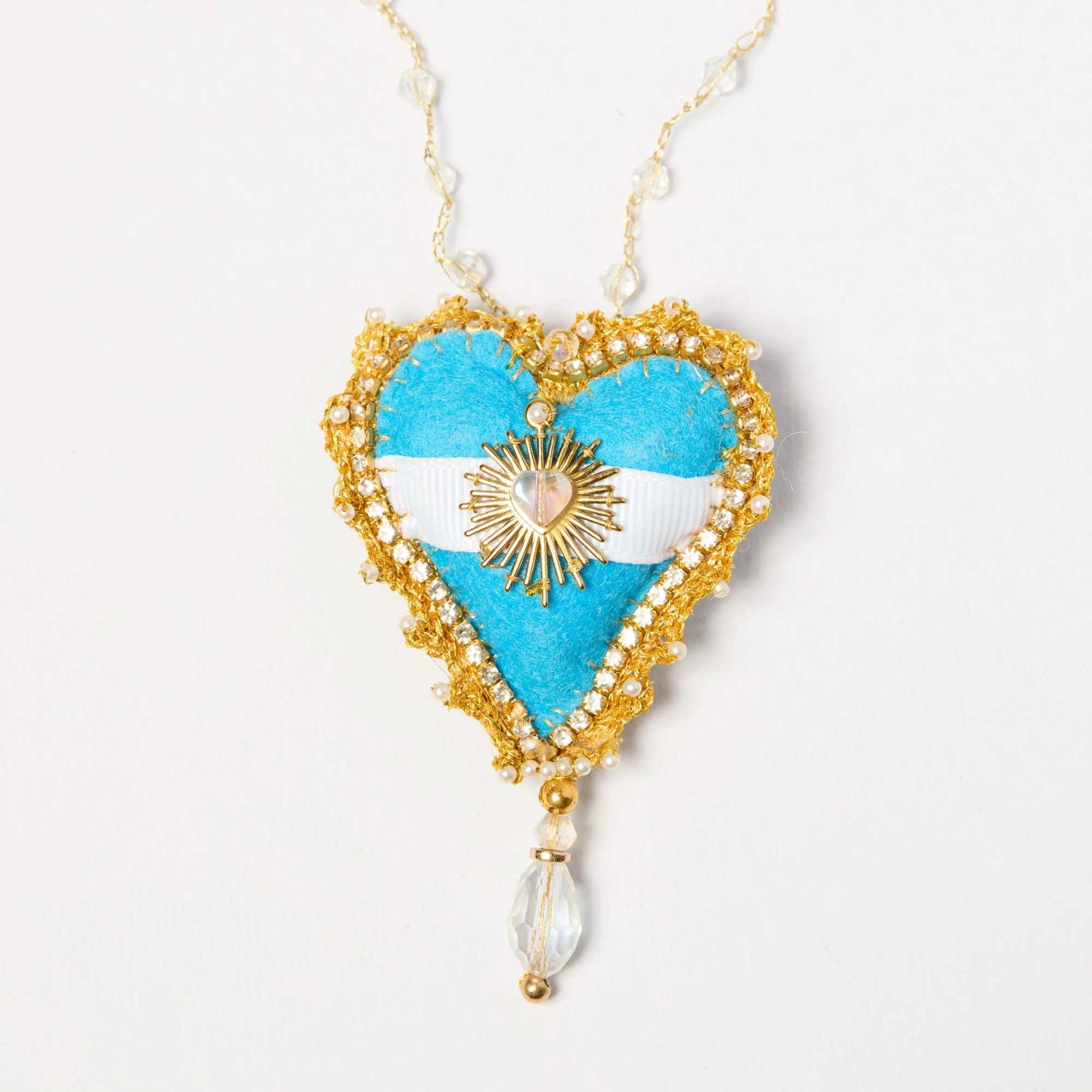 A decorative necklace with blue, gold, and pearl accents, featuring a heart and star motif on a white background.