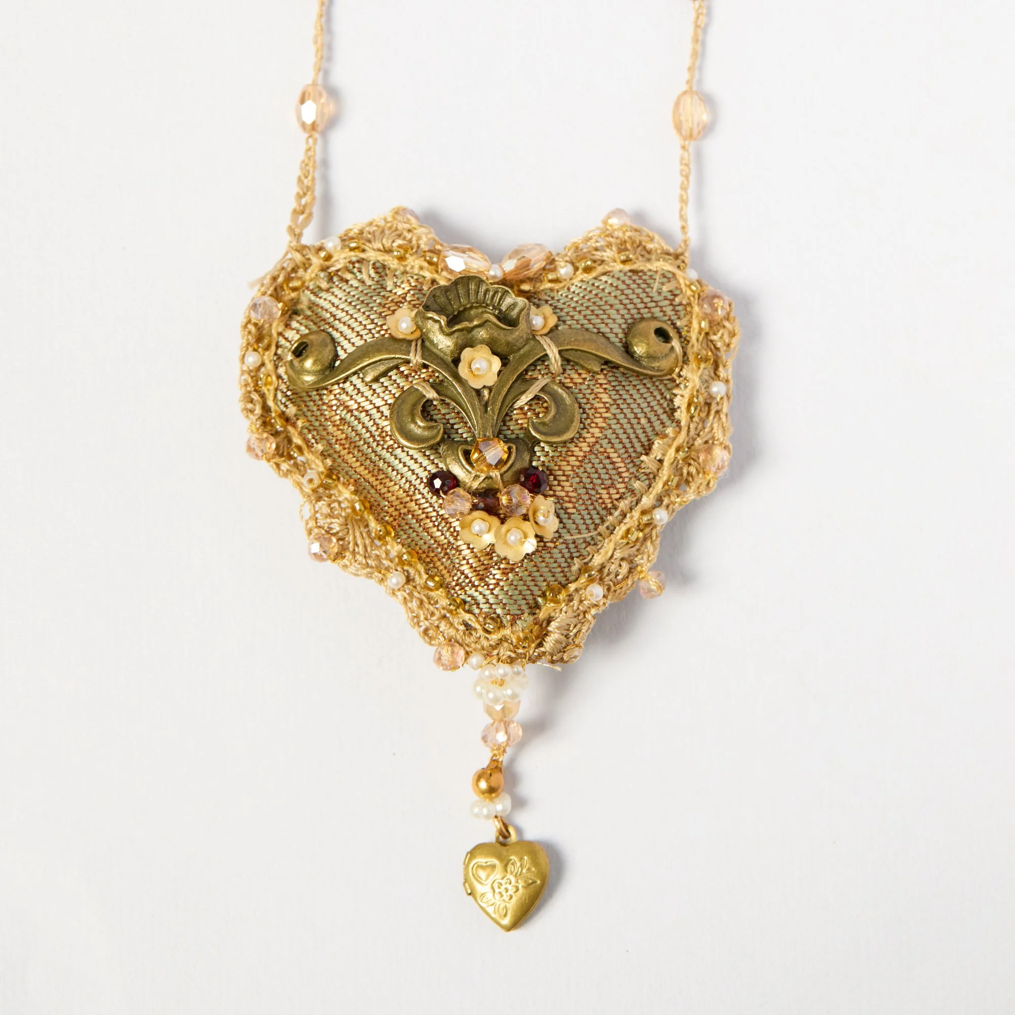 Gold and pearl necklace with heart-shaped pendant and floral embellishments, hanging against a white background.