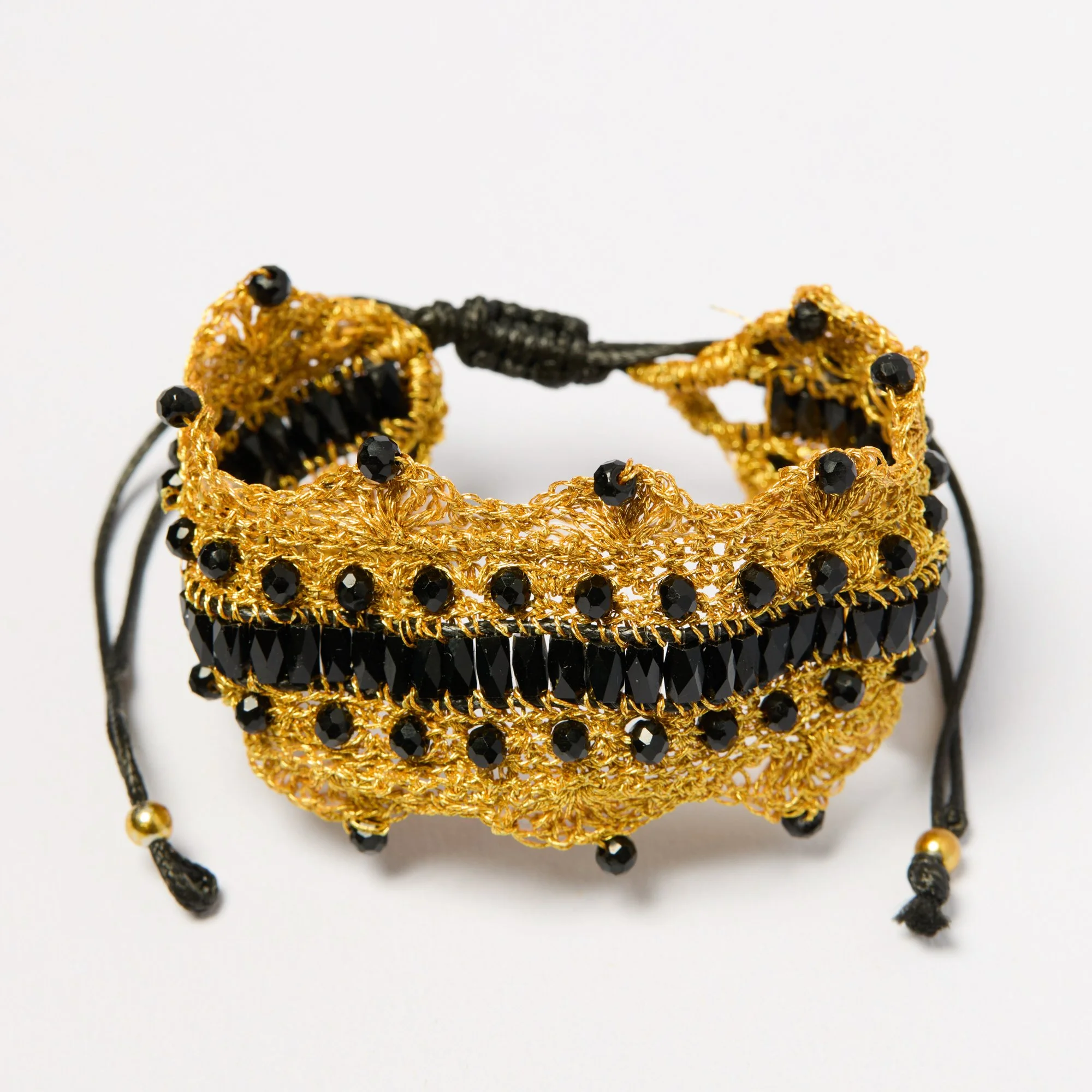Gold and black beaded earrings with black beads and gold thread accents displayed against a white background.