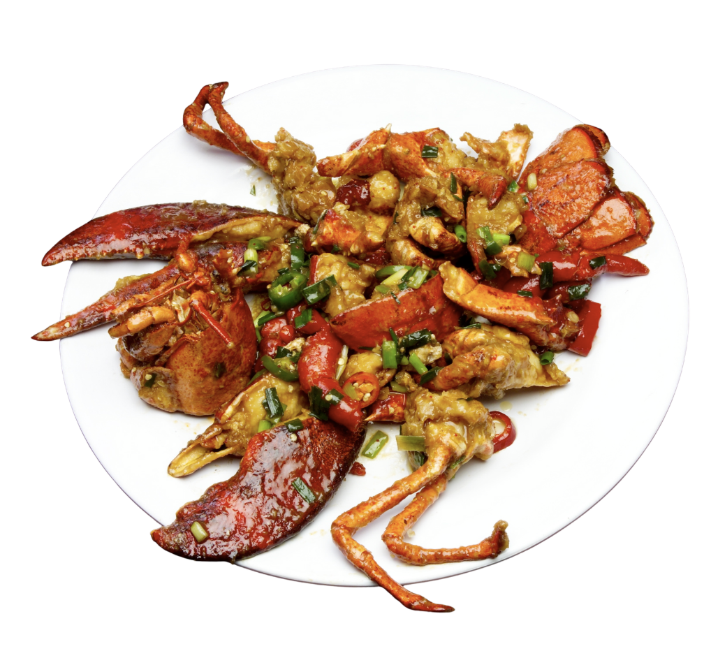 A plate of cooked lobster with chopped green onions and a spicy sauce.