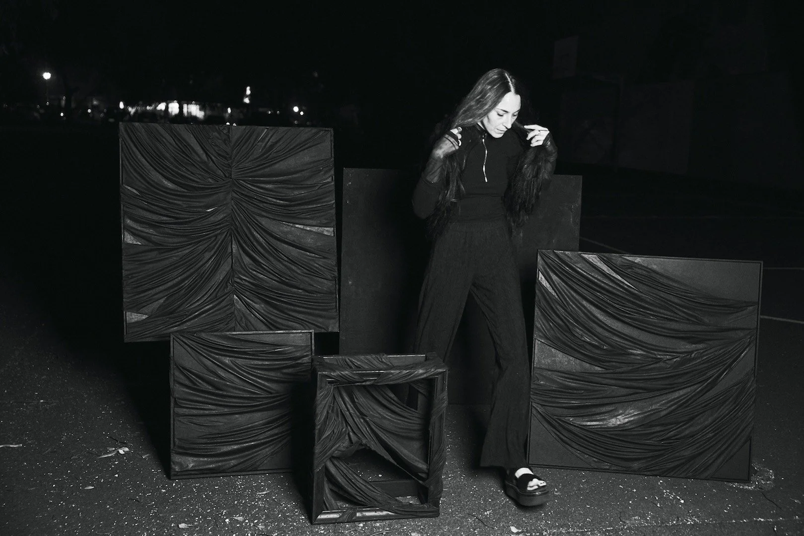 Stephanie Jook standing with a collection of her sculptural and textural paintings.