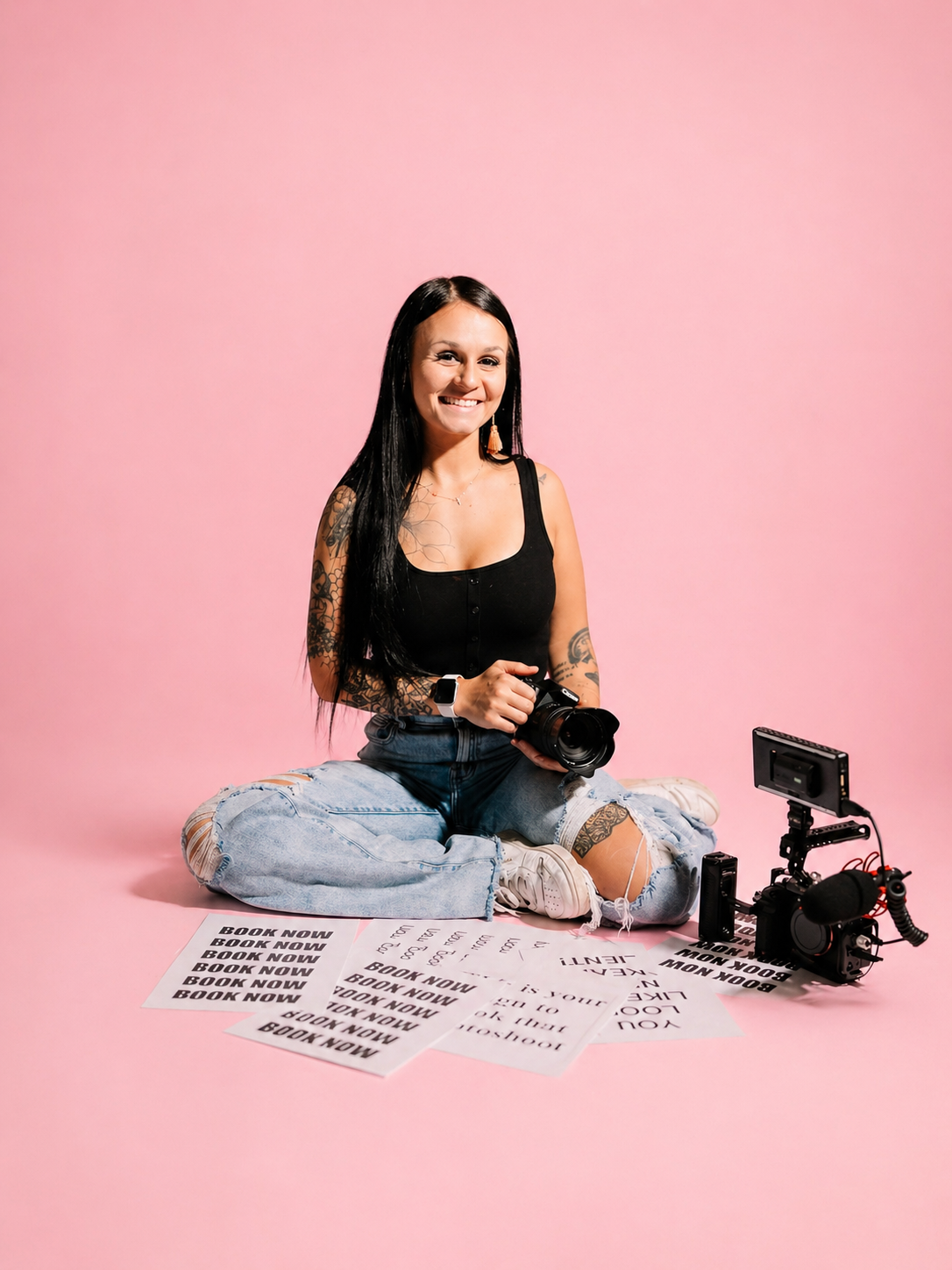 Kansas City brand photography session, woman with tattoos sitting on a pink background holding a camera