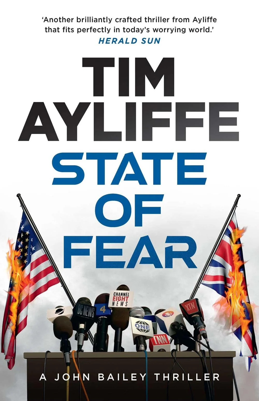 Book cover for 'State of Fear' by Tim Ayliffe, featuring microphones from various news outlets on a table and burning American flags.