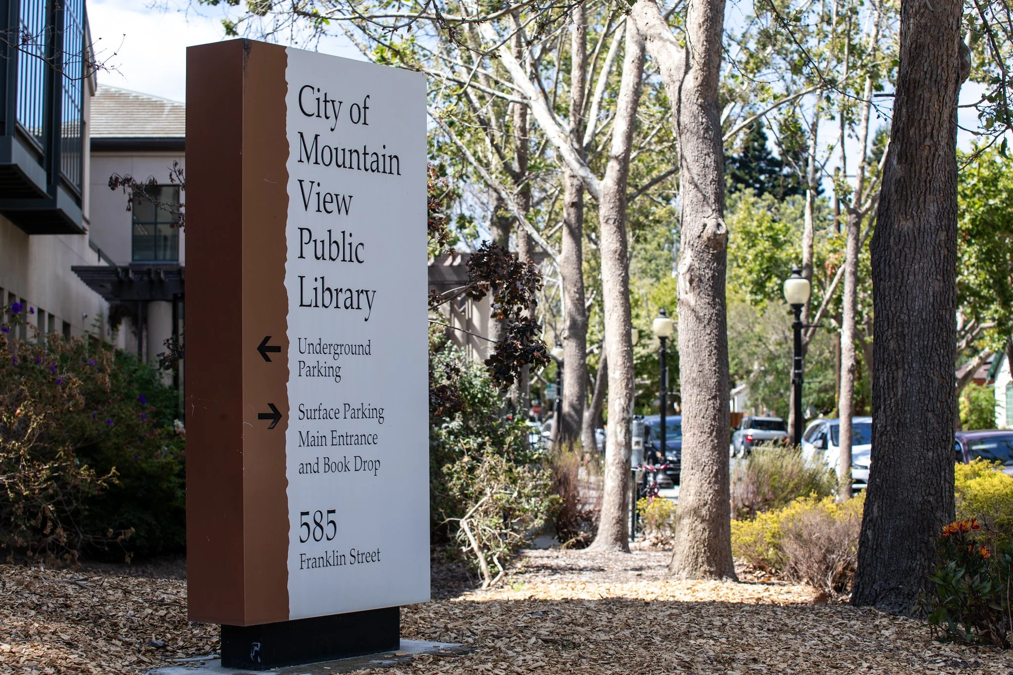 Sign for City of Mountain View Public Library with directions to underground parking on the left, surface parking, main entrance, and book drop on the right, located on Franklin Street.