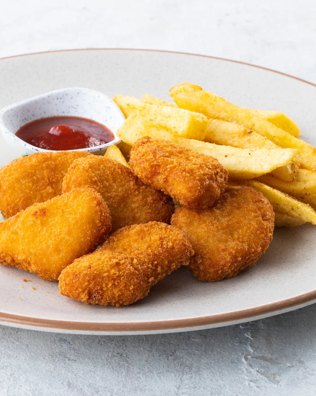 Fried fish fillets with French fries, served with ketchup on a white plate.