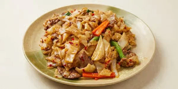 Plate of stir-fried noodles with beef and vegetables.