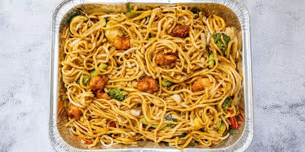 Takeout container of stir-fried noodles with broccoli, chicken, and vegetables.