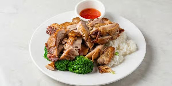 Plate with cooked chicken, broccoli, and white rice, served with a small bowl of red dipping sauce.