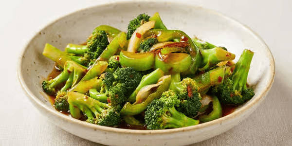A bowl of cooked broccoli with sauce