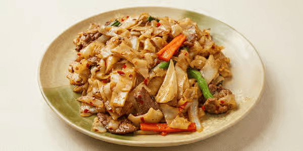 Stir-fried noodles with beef and vegetables on a white plate