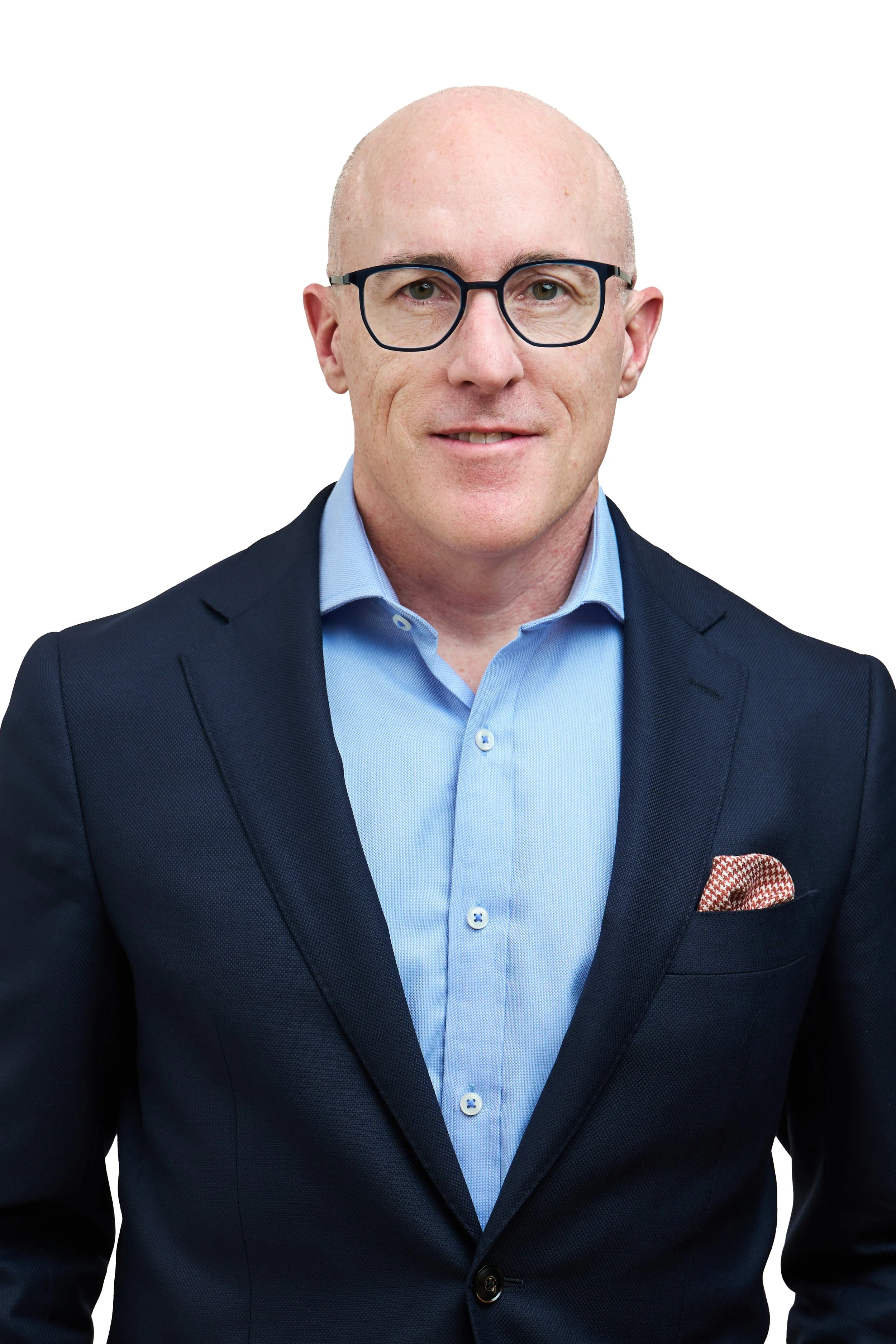 A bald man wearing glasses, a blue dress shirt, and a navy blazer with a pocket square, posing against a white background.